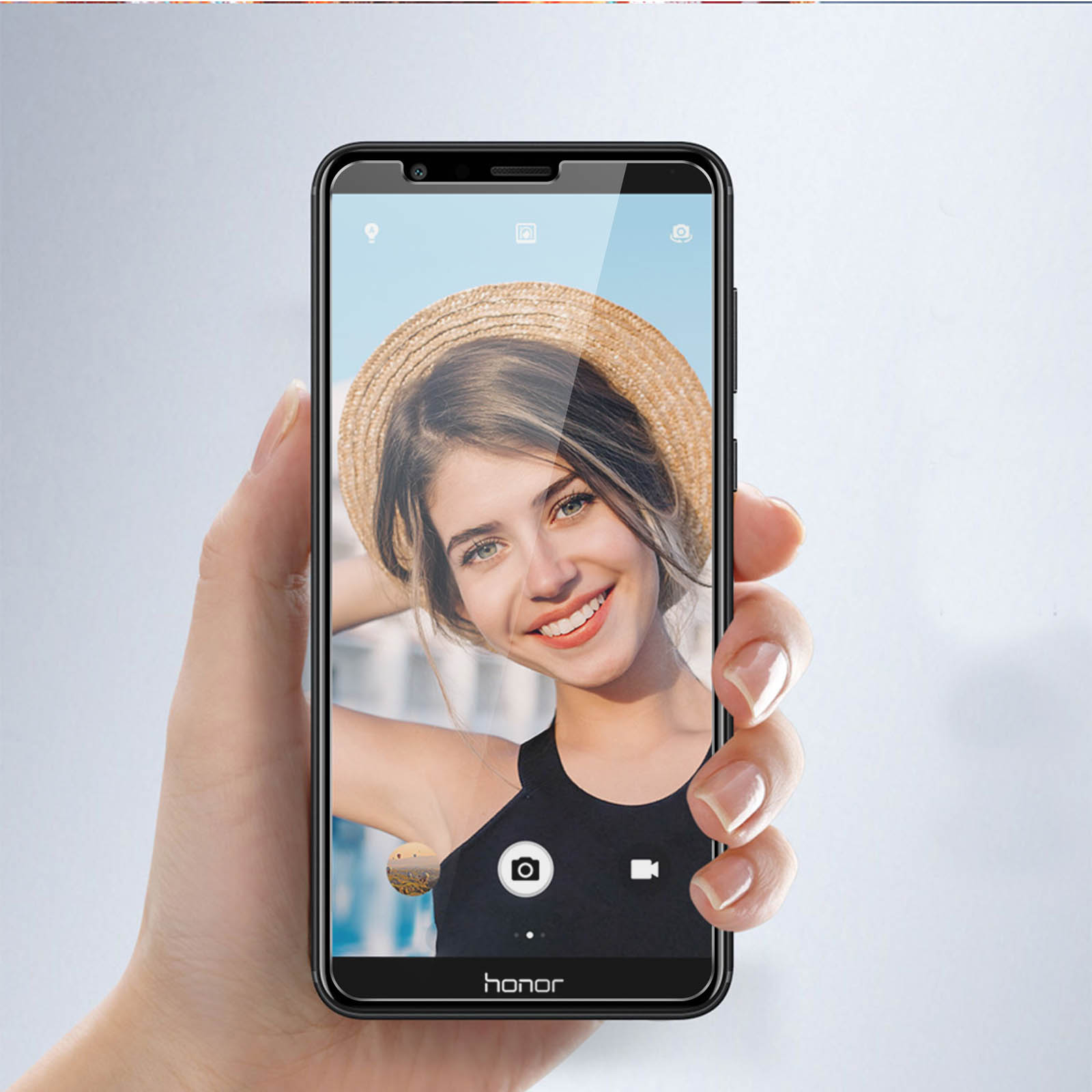 Una mano tiene uno smartphone nero che mostra una donna sorridente che fa un selfie.