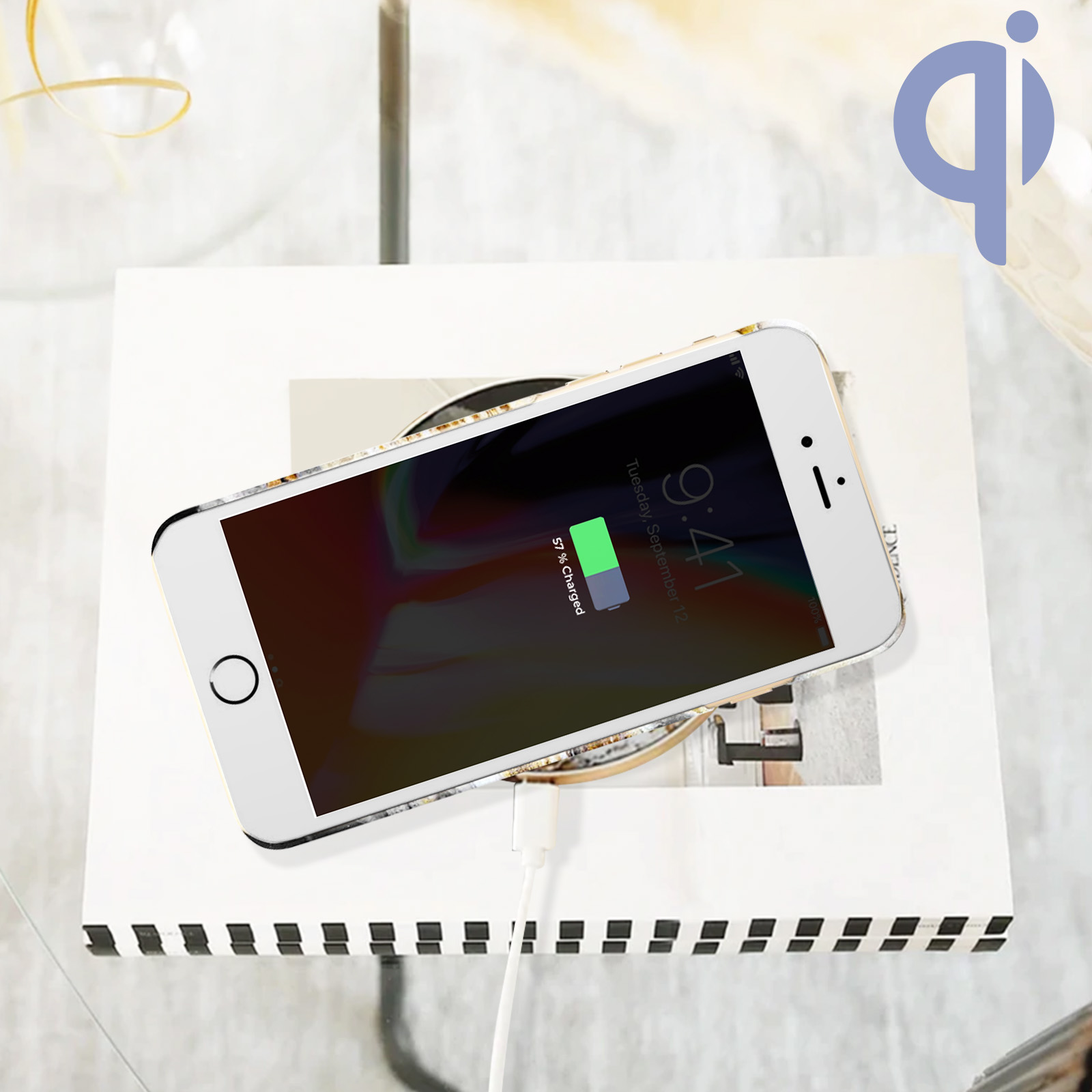 Un telefono si carica in modalità wireless su una superficie bianca. Lo schermo mostra 57% caricato. Logo qi.