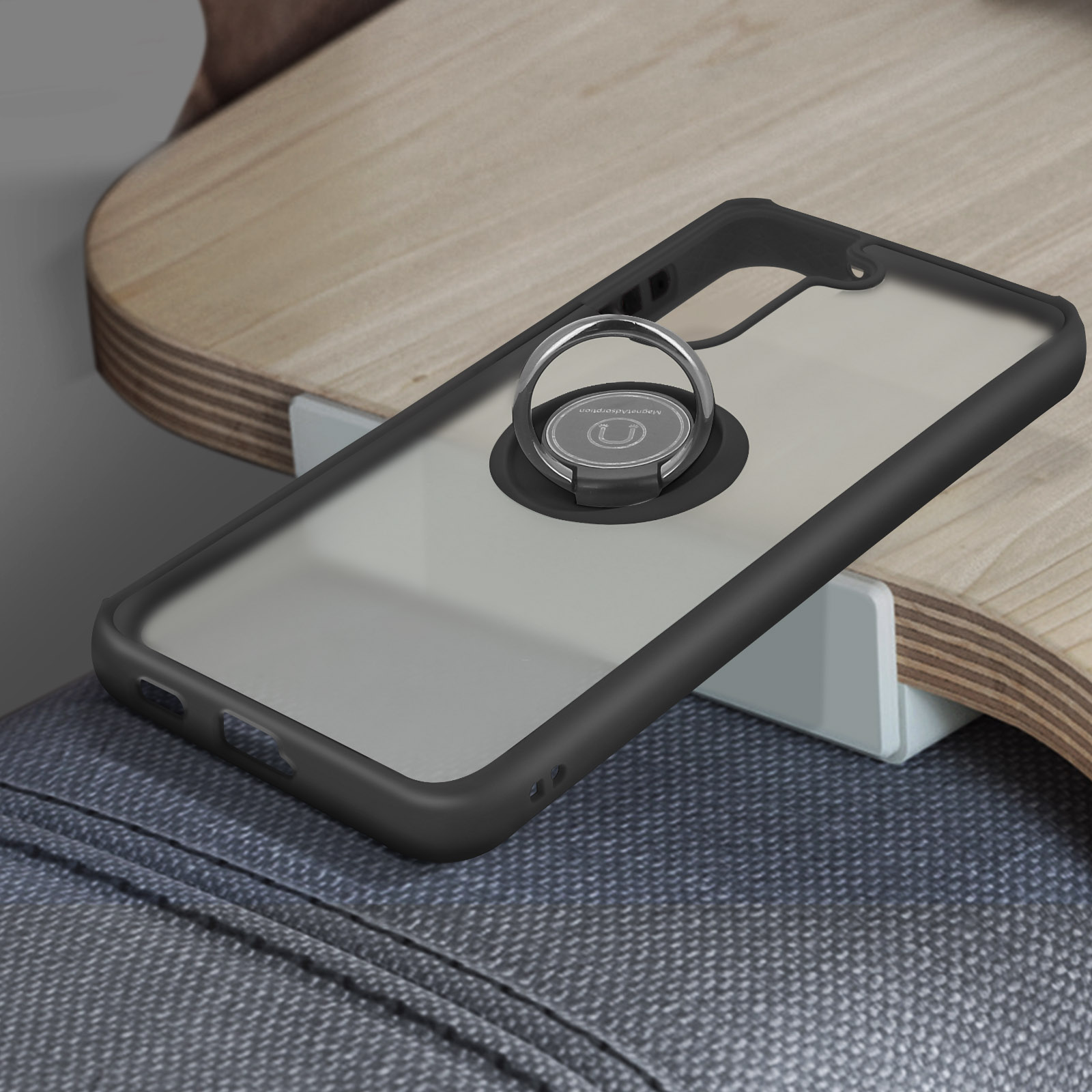 Un étui de téléphone noir avec un support d'anneau. L'étui est sur une table en bois.