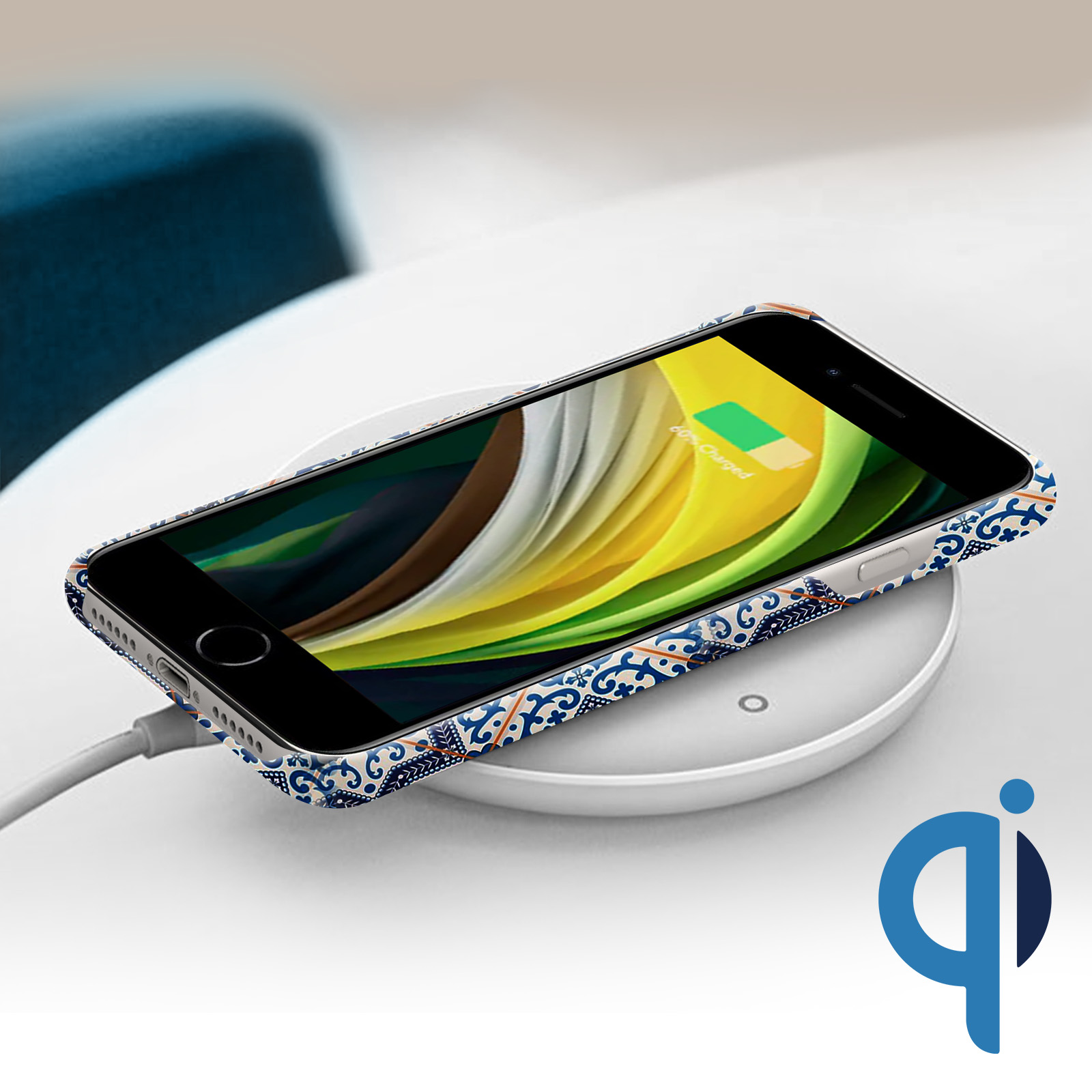 Telefono su caricatore wireless. Il telefono ha una custodia con motivo blu. Caricatore con logo Qi.