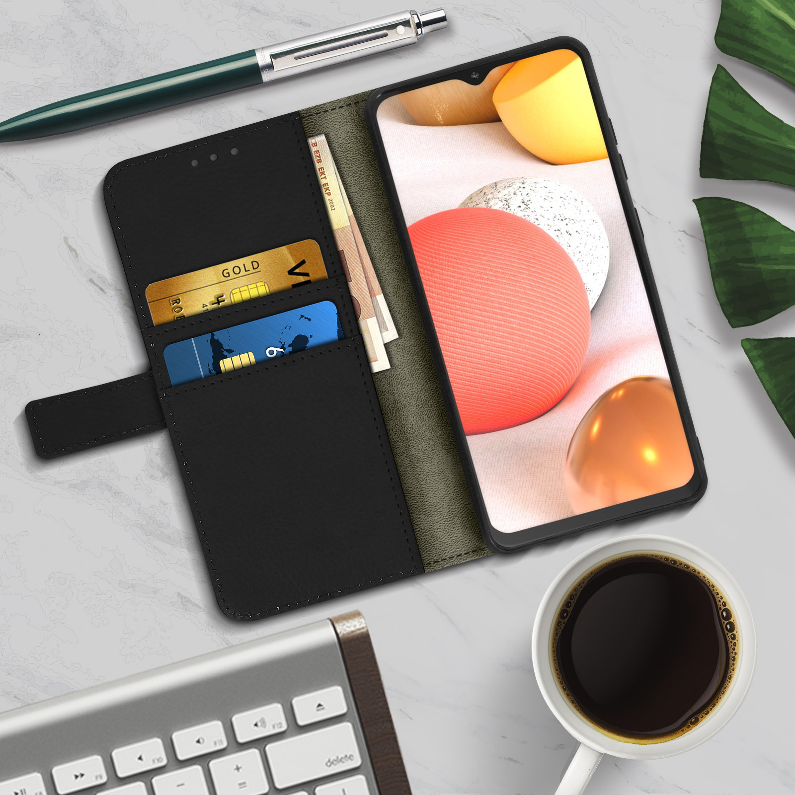Una custodia per telefono aperta, sono visibili carte e denaro. Vicino c'è una tazza di caffè e una tastiera.