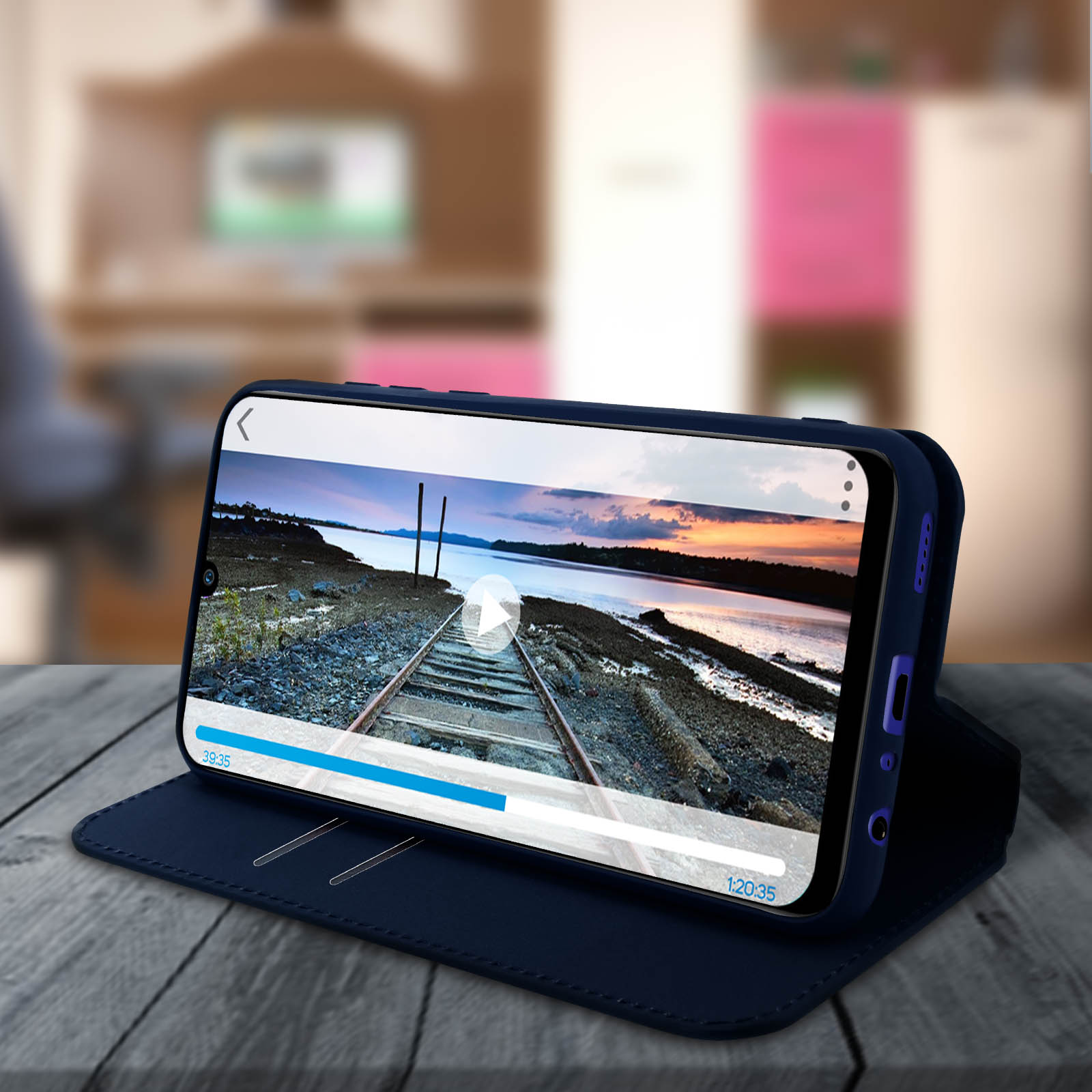 Un telefono che mostra un video su una custodia blu, in posizione verticale. Lo schermo mostra un binario.