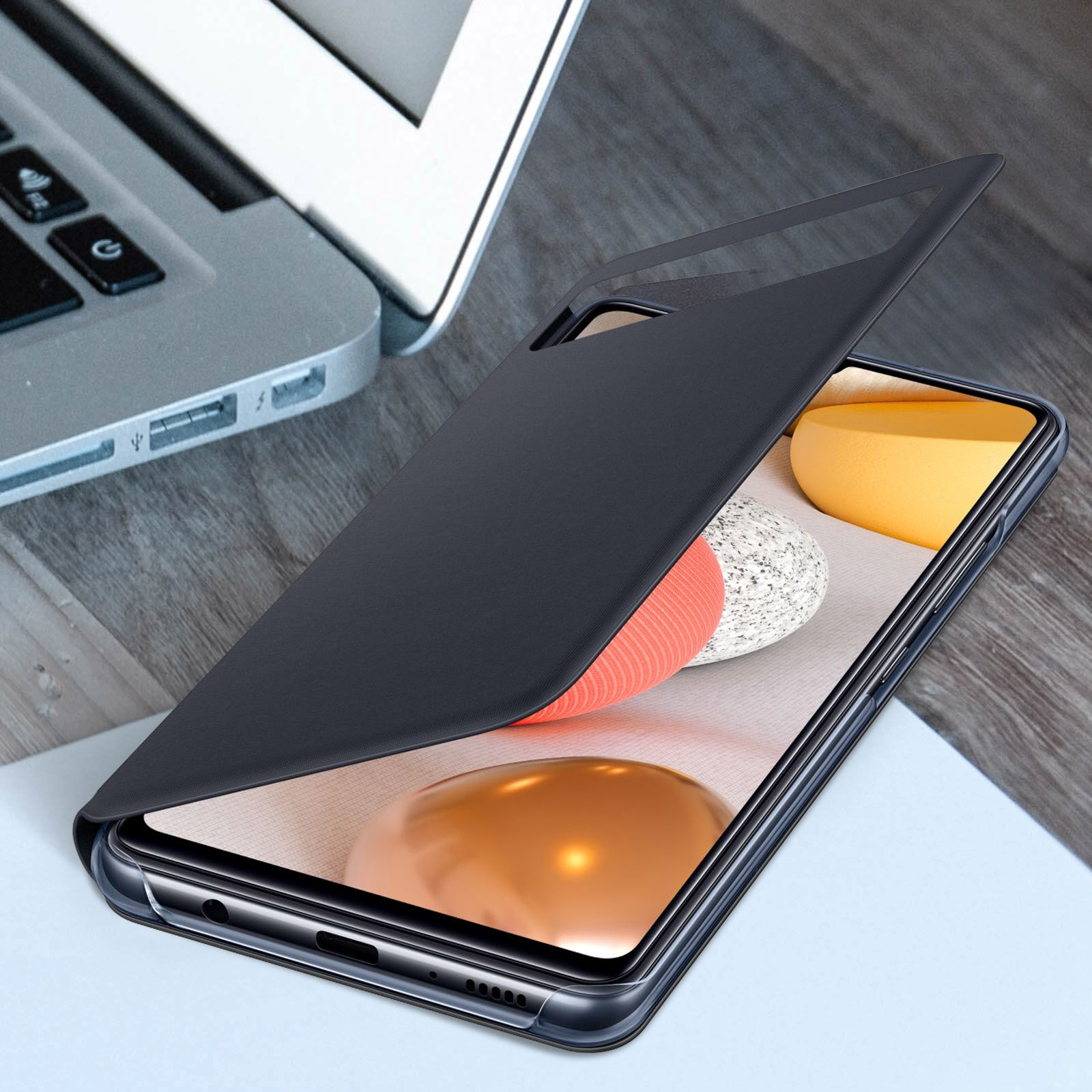 Teléfono negro con funda transparente, sobre una mesa de madera.