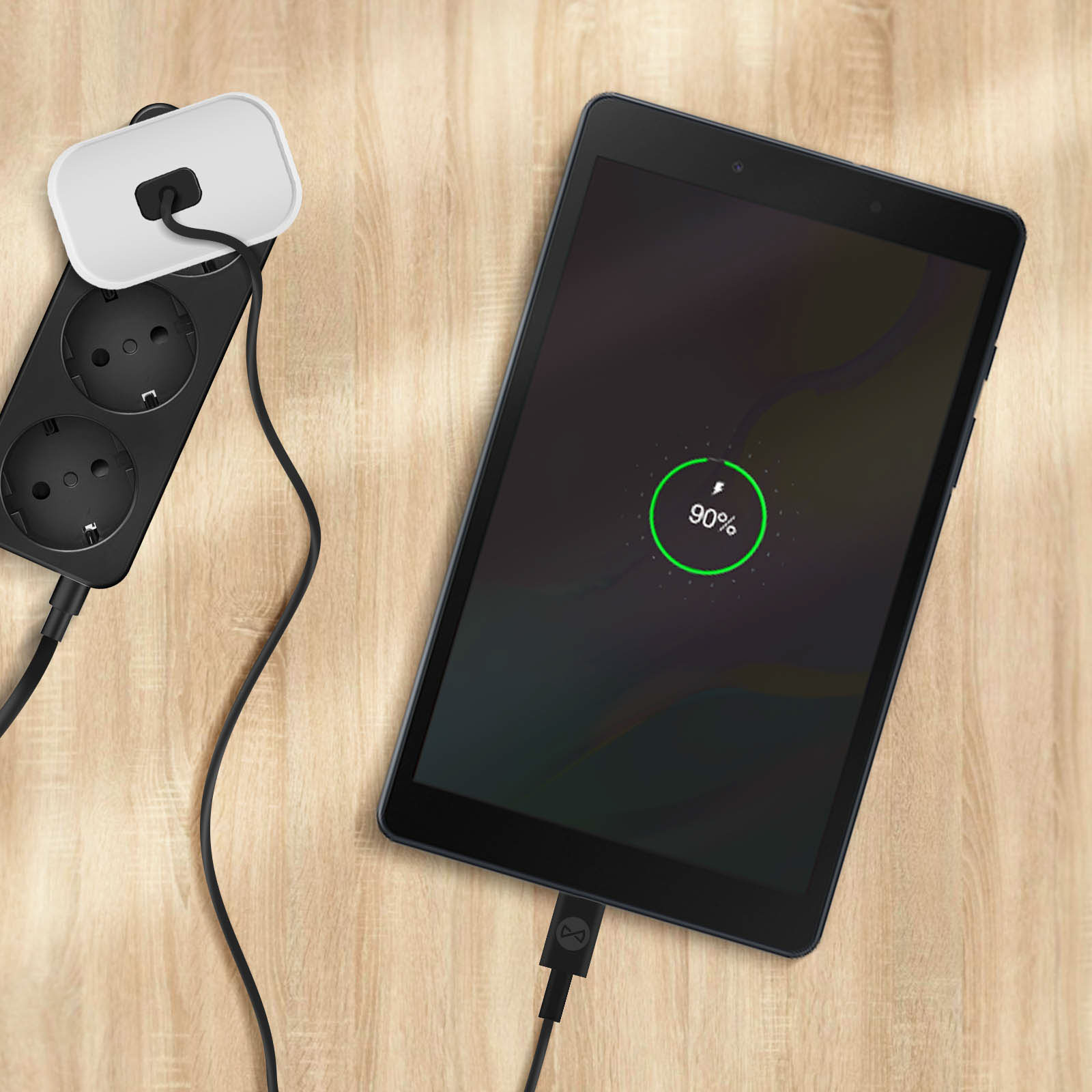 Tablet in carica con 90% di batteria. Sfondo: legno. Un cavo nero è collegato al tablet e alla presa.