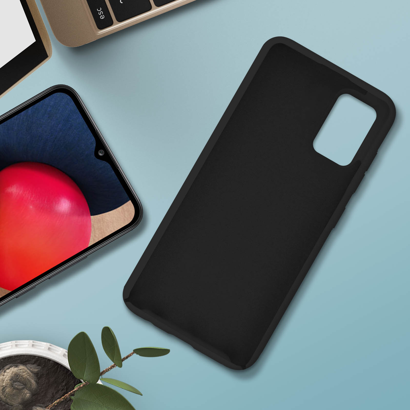 Custodia e telefono neri su una superficie blu. Una pianta e un laptop sono sullo sfondo.