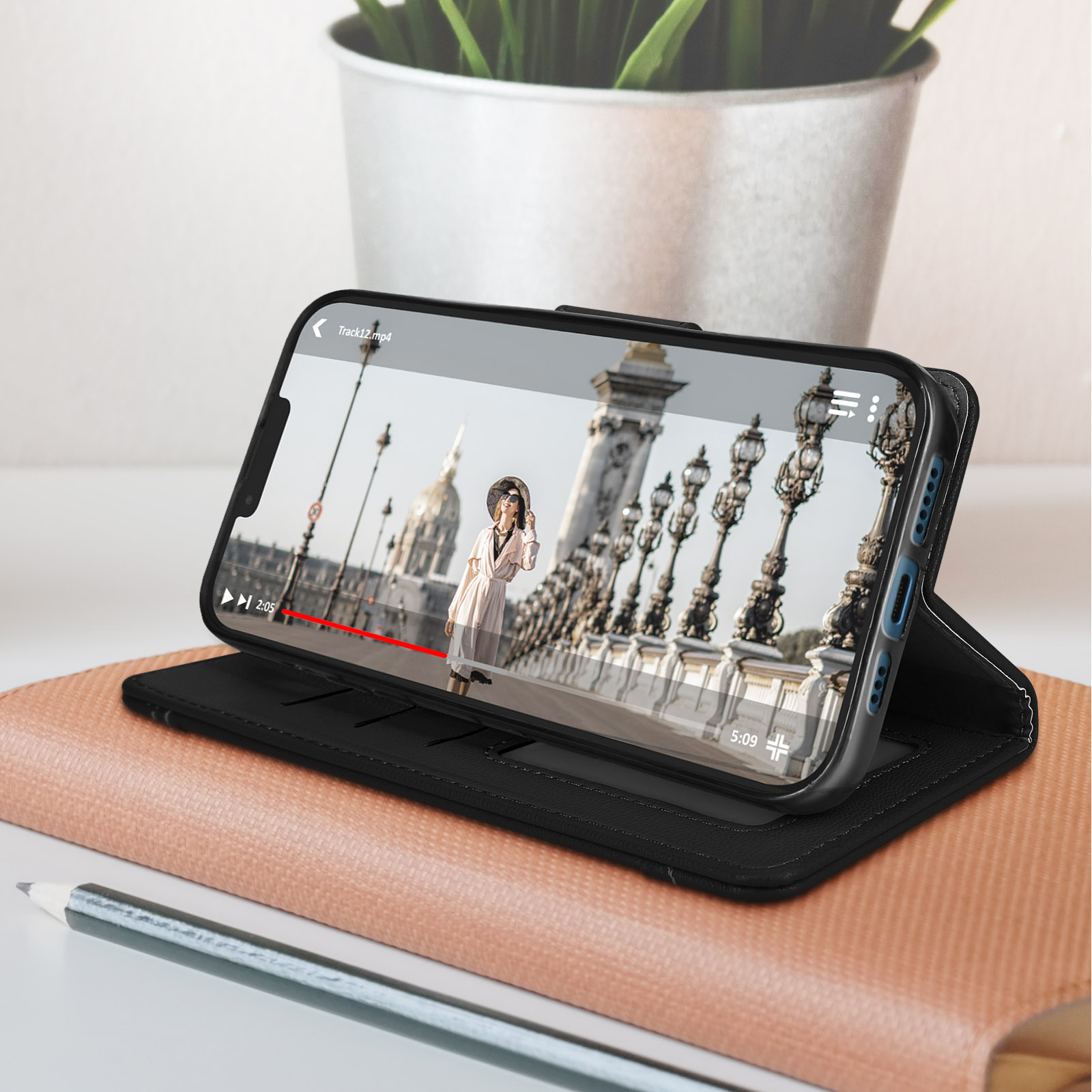 Téléphone affichant vidéo d'un pont, dans un étui cuir marron.
