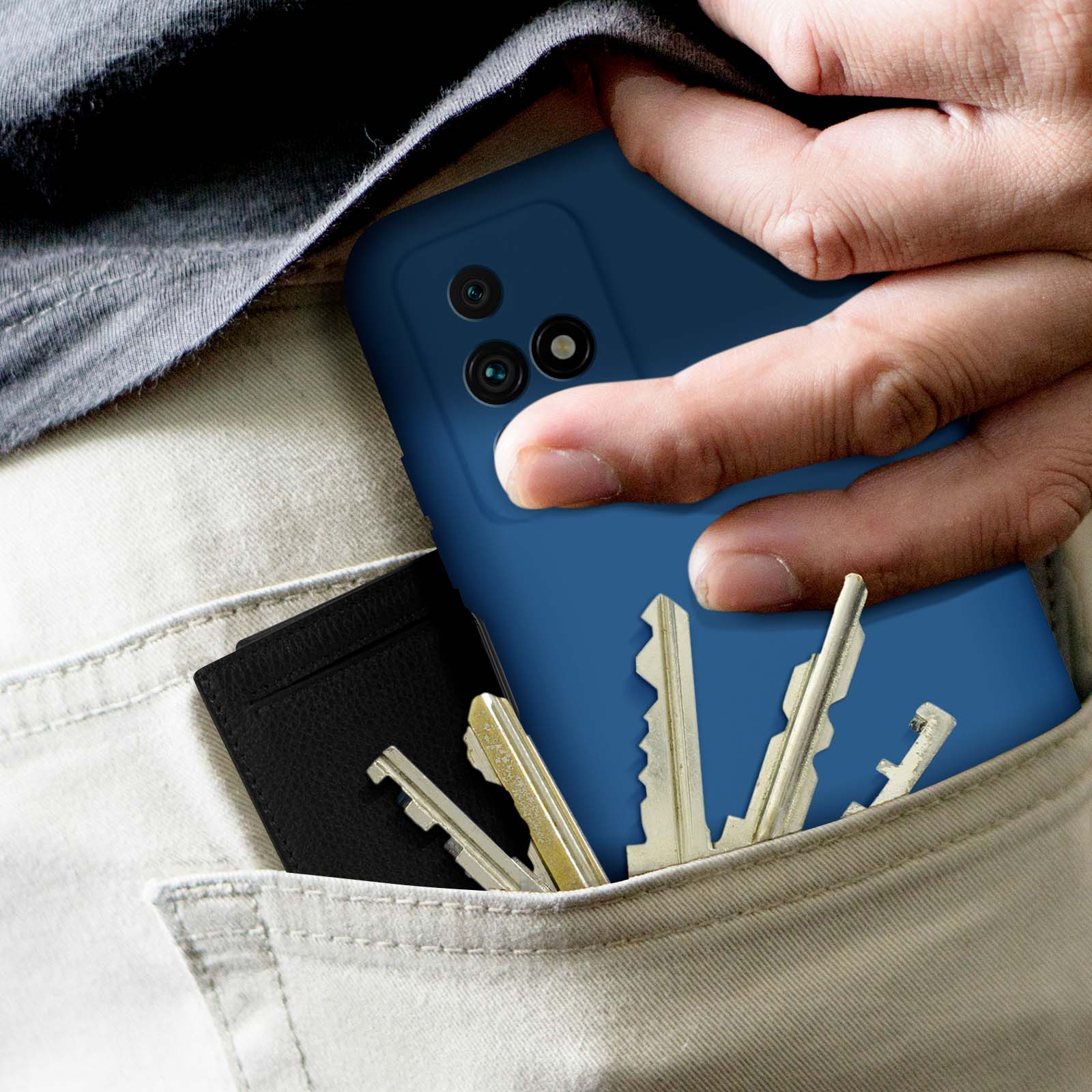 Mano in tasca con telefono blu, chiavi e portafoglio. Pantaloni beige visibili.