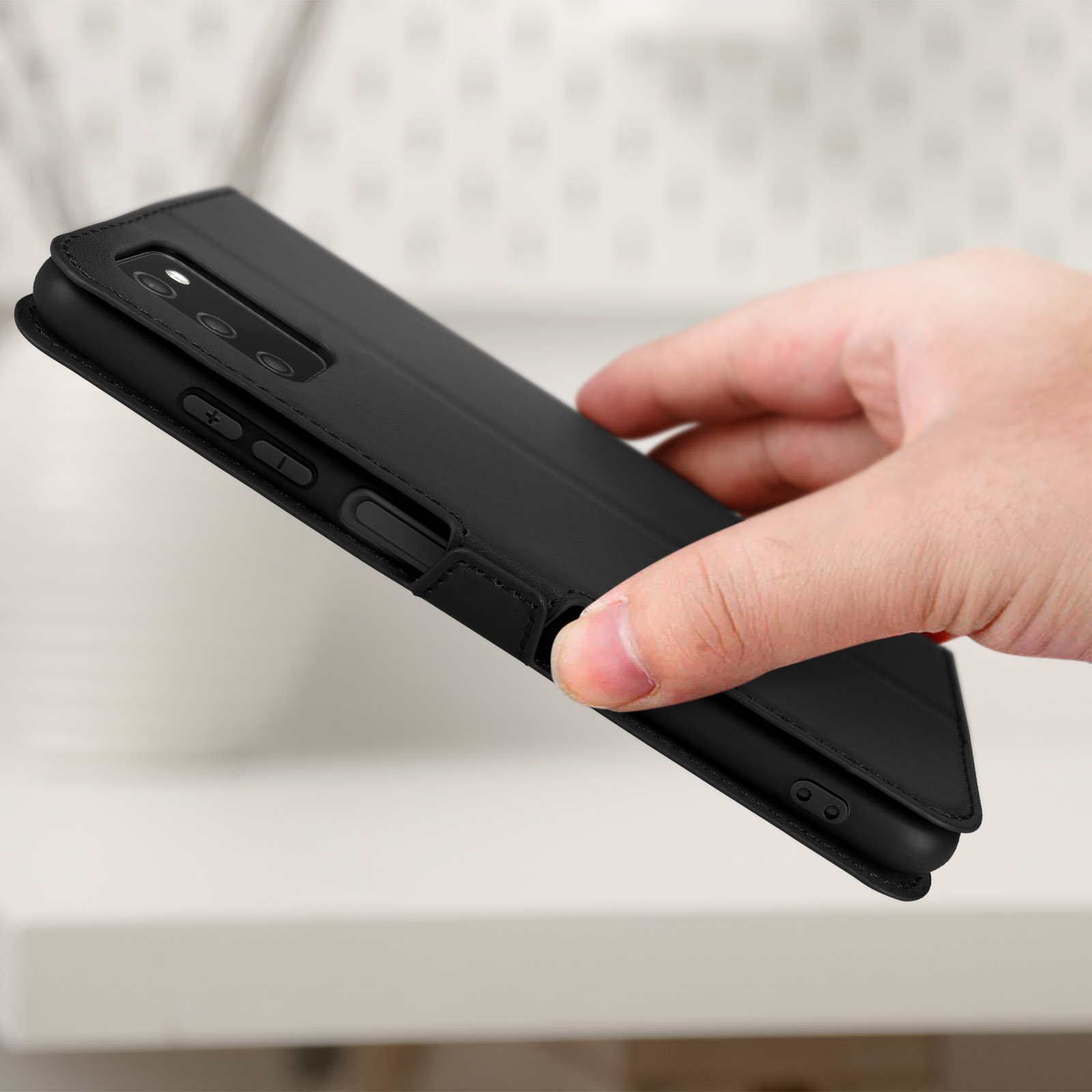 Zwarte telefoonhoes, vastgehouden door een hand op een wit oppervlak.