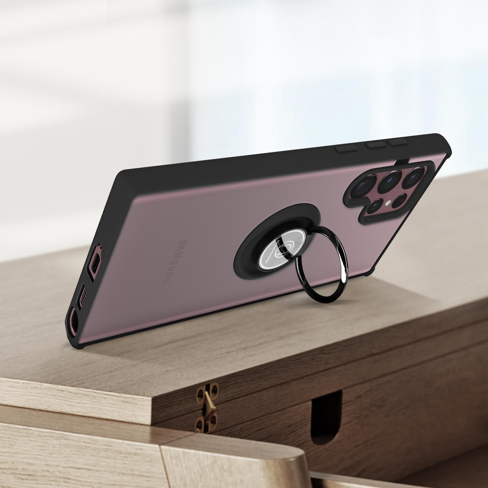 Téléphone dans un étui avec support anneau sur table en bois. Noir et violet.