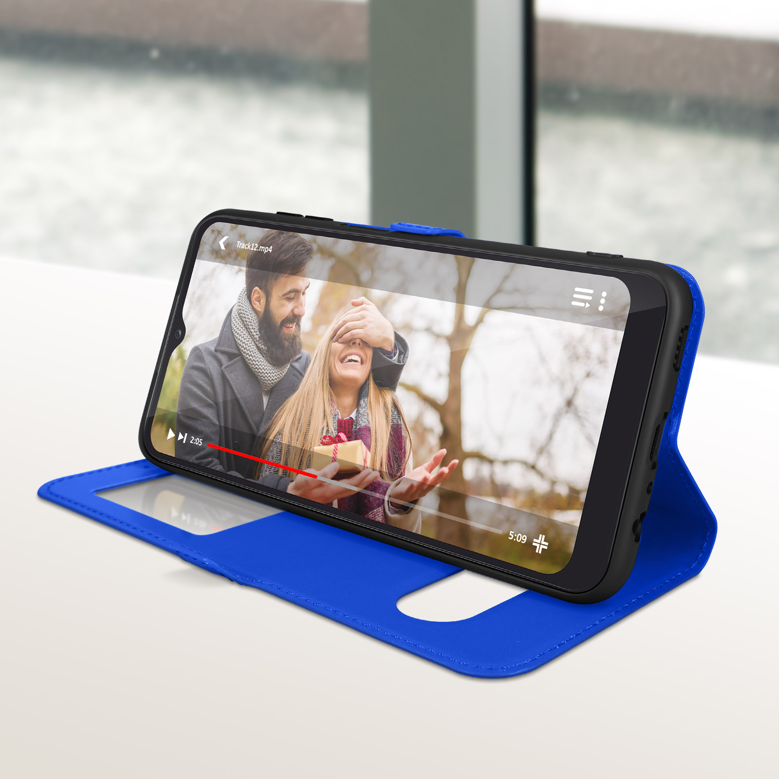 Een telefoon in een blauwe hoes toont een video van een stel. De hoes ligt op een witte tafel.