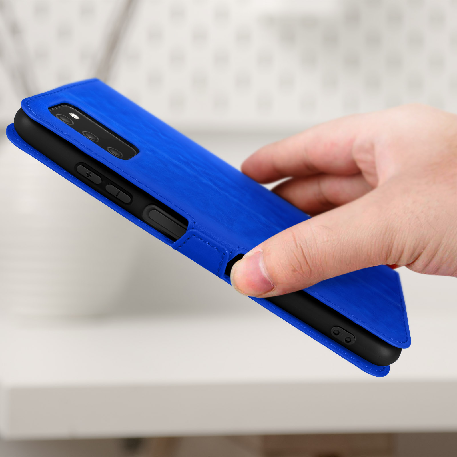 Hand die een blauwe telefoonhoes vasthoudt, de telefoon binnenin is gedeeltelijk zichtbaar.