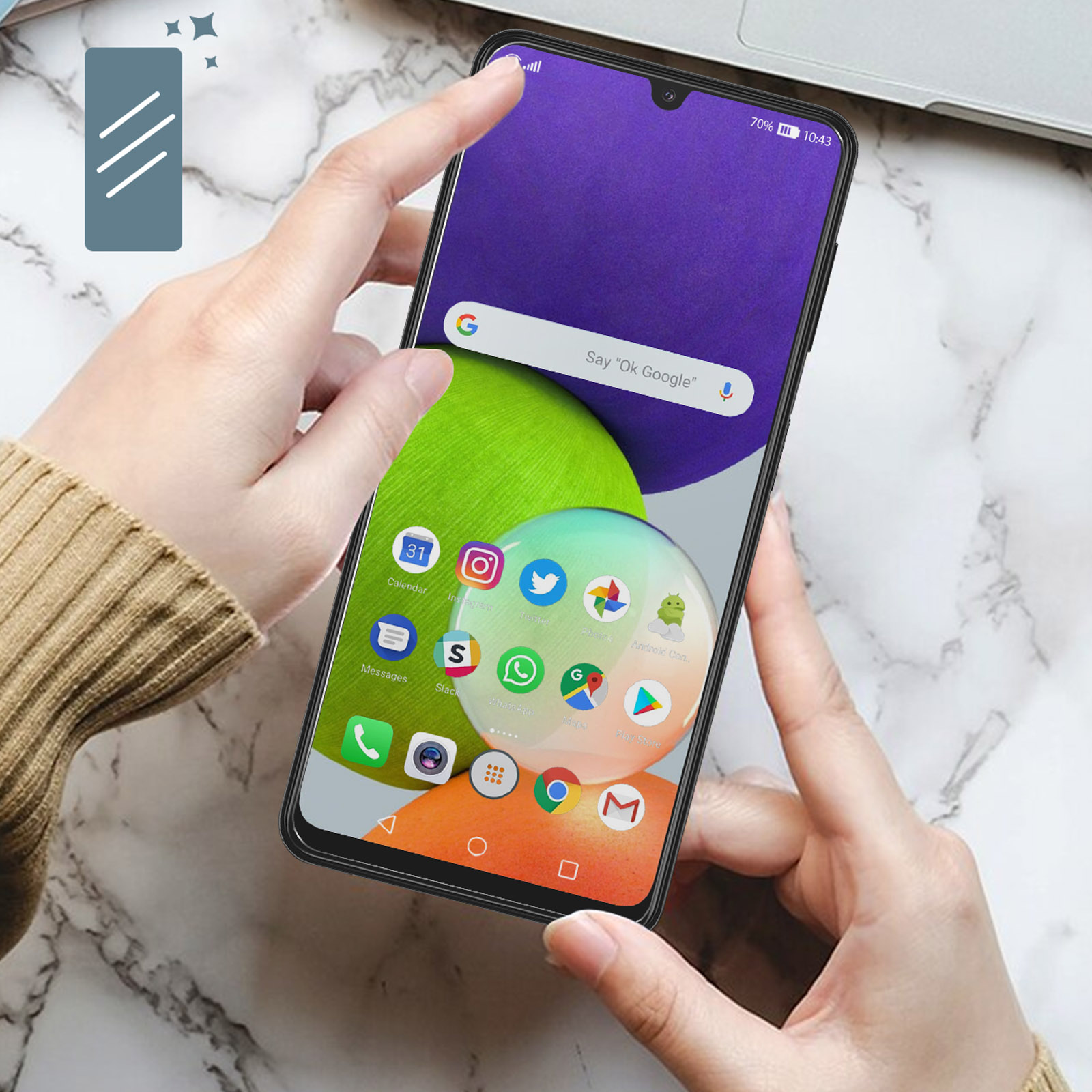 Una persona tiene in mano uno smartphone. Lo schermo del telefono mostra le icone delle app e un messaggio 'Ok Google'.