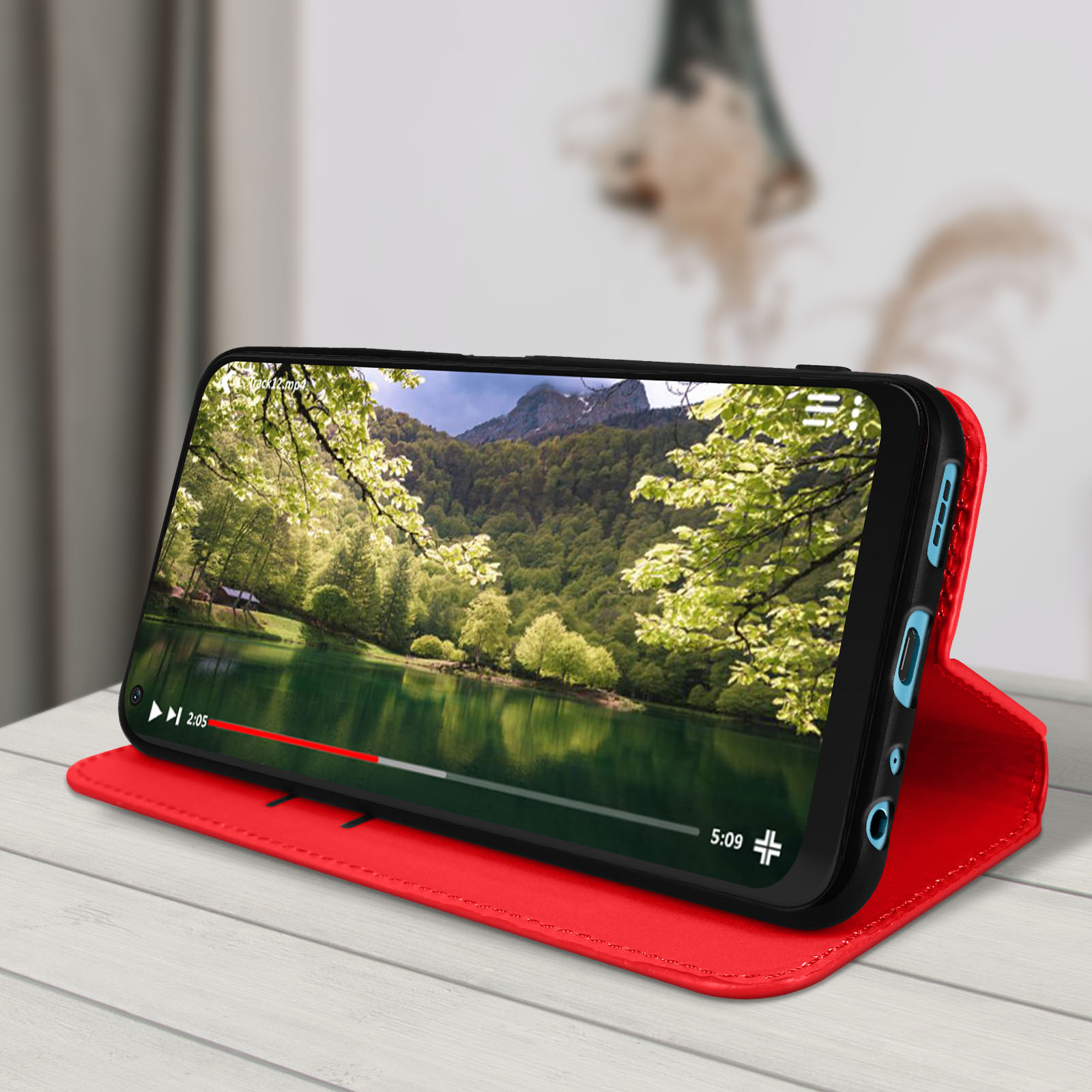 Un téléphone affiche une scène de lac dans un étui rouge pliable sur une surface en bois.