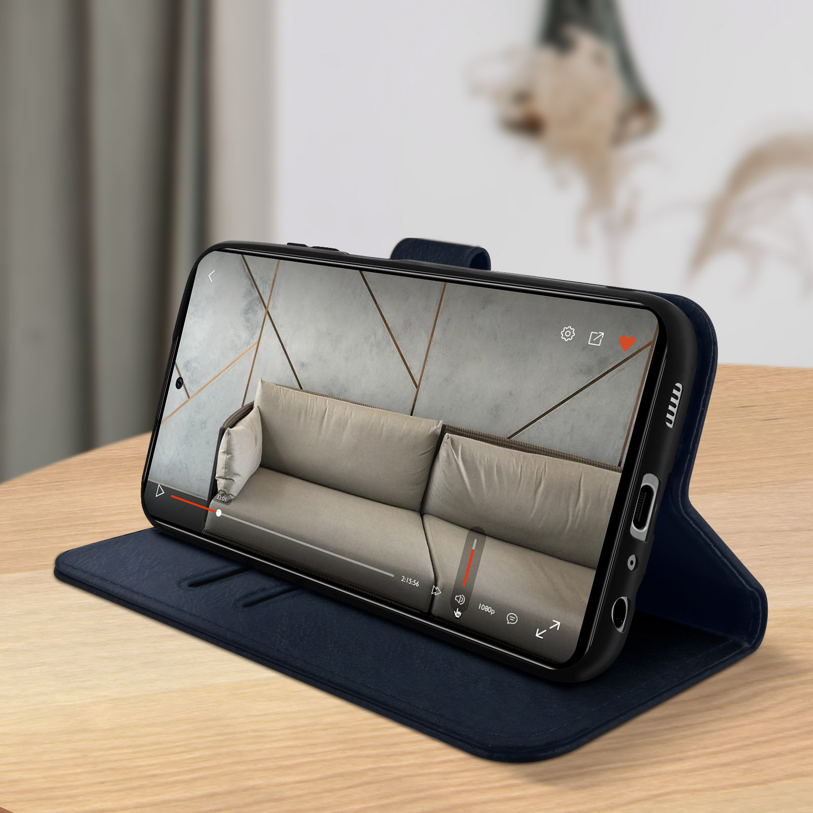 Telefoon die een video afspeelt, in een blauwe telefoonhoes. Achtergrond heeft een beige bank en wandkunst.