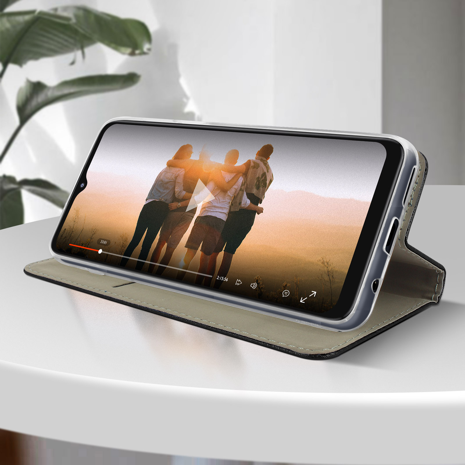Smartphone che mostra video di persone che si abbracciano, su tavolo bianco. Telefono con custodia.