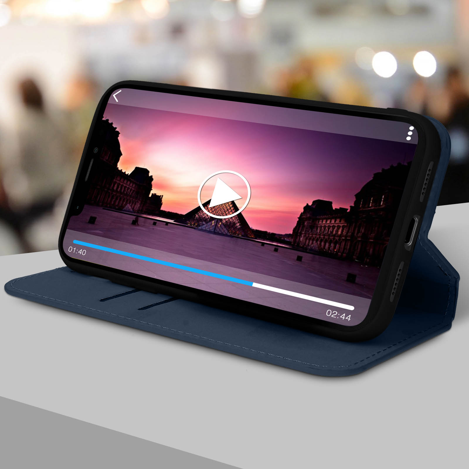 Un telefono che mostra un video con una città europea sullo sfondo, in una custodia blu.