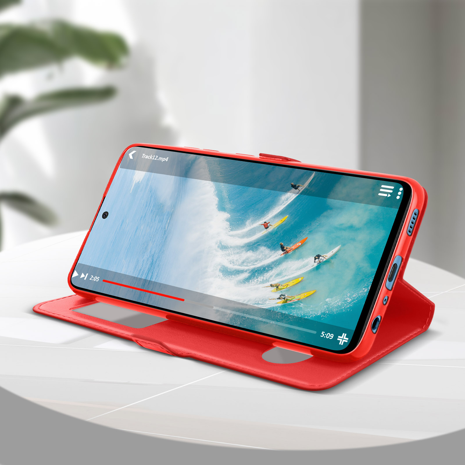 Custodia rossa per telefono con telefono che mostra un video di surfisti su un supporto.