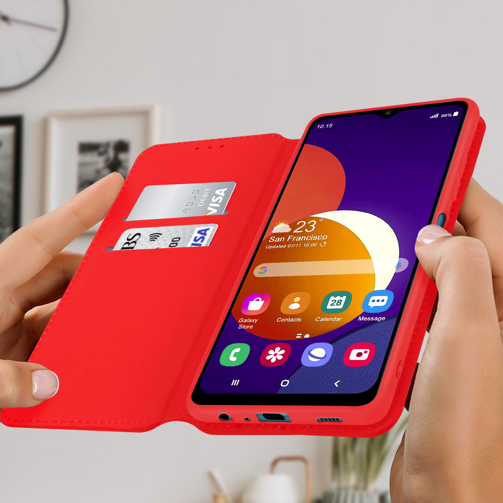 Custodia rossa per telefono con telefono dentro. Carta di credito nella custodia. Mani che la tengono.