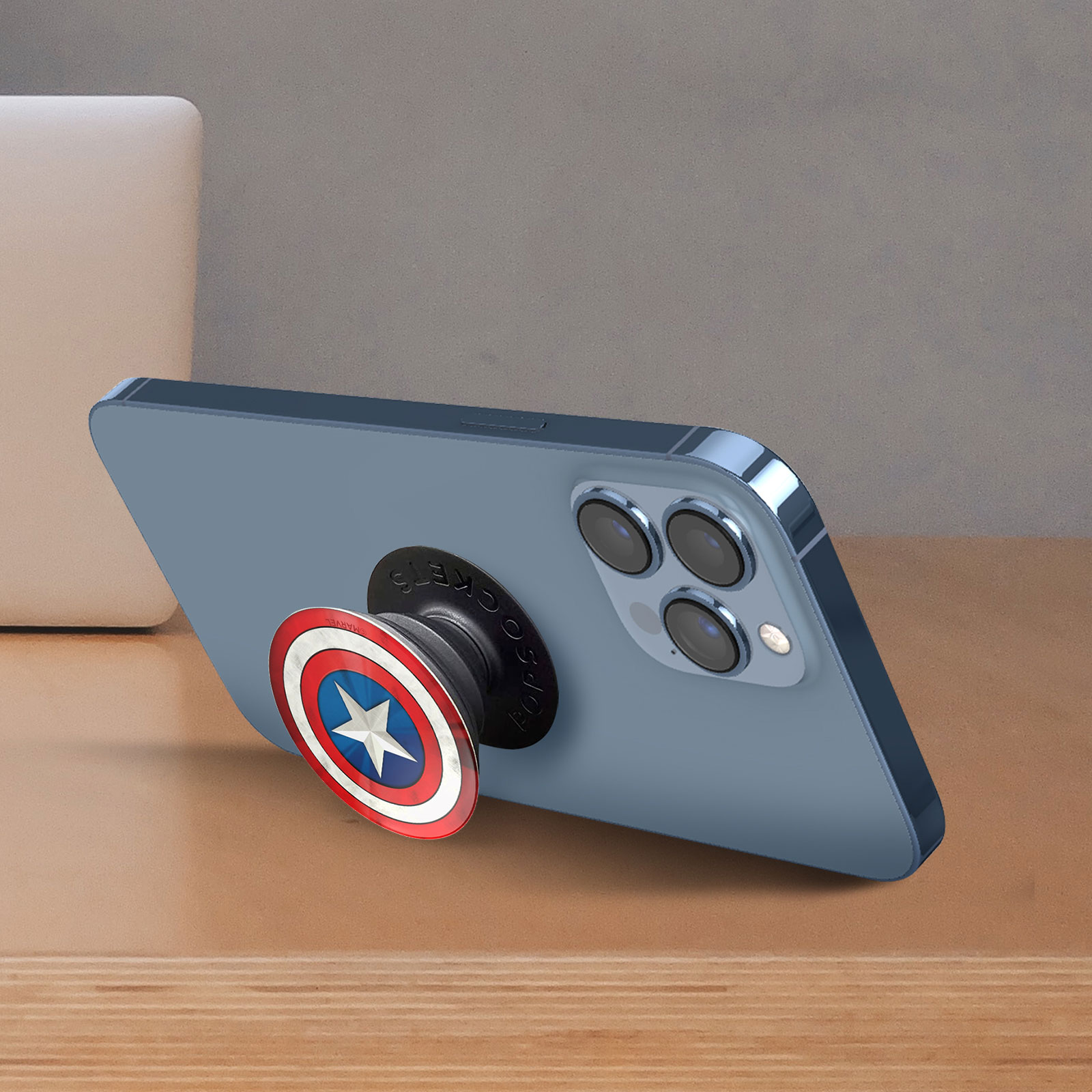 Ein Telefon mit einem Captain America PopSocket auf einer Holzoberfläche.