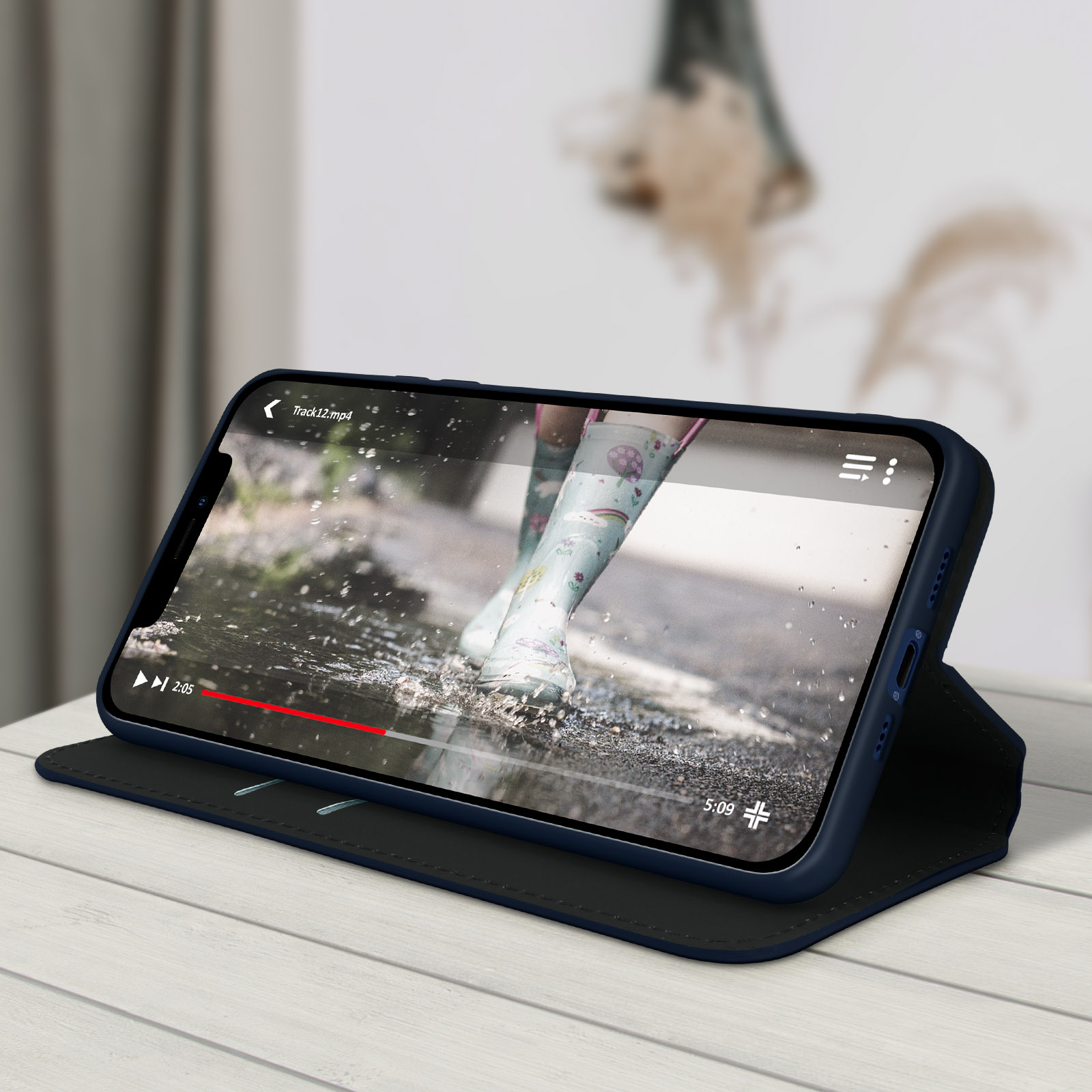 Een telefoon die een video afspeelt. Toont benen in regenlaarzen in een plas.
