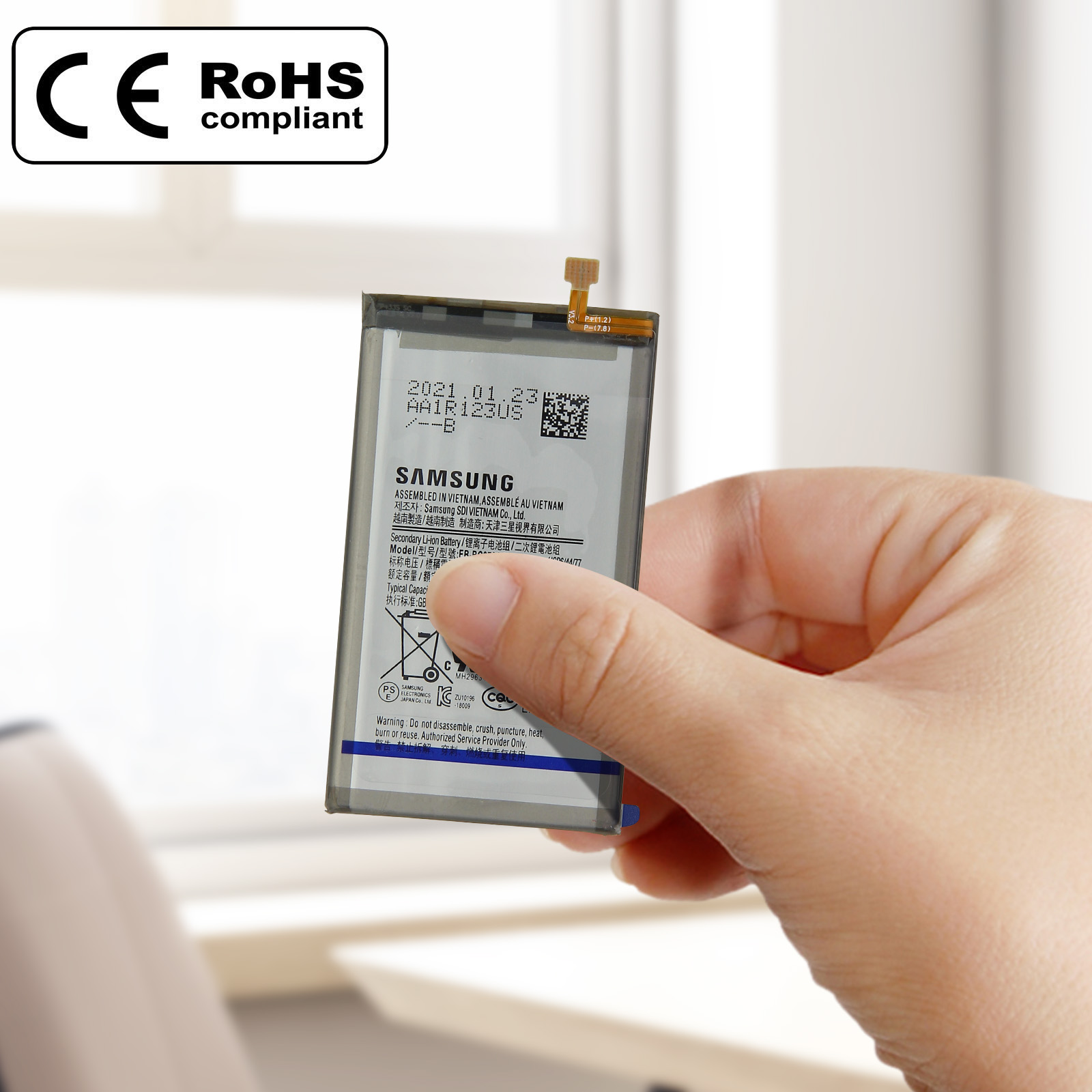 Hand hält Telefonbatterie mit Etikett, ein RoHS-konformes Logo ist sichtbar.