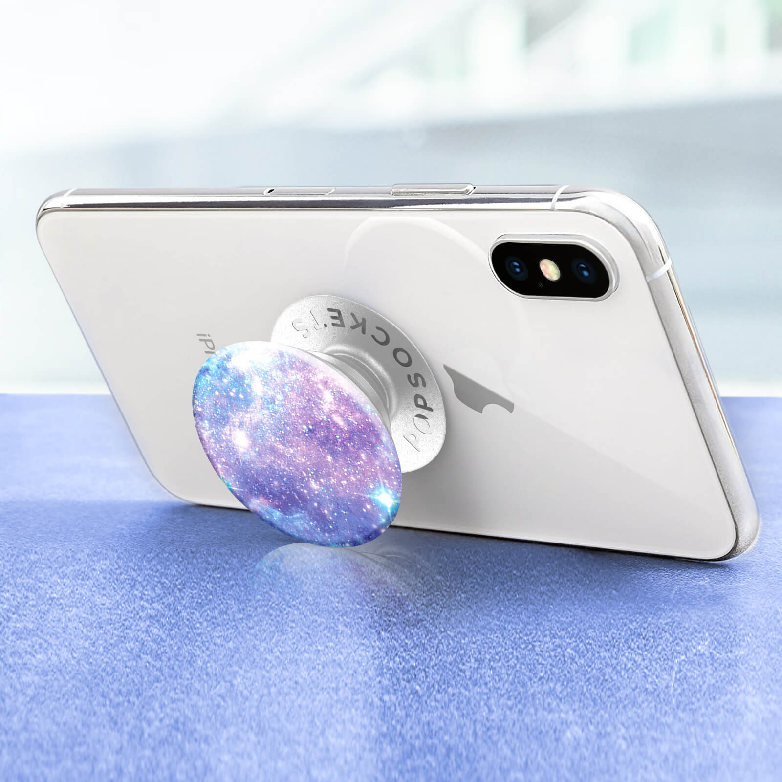 Ein weißes Telefon mit einem Pop-Socket befestigt. Der Pop-Socket hat ein Galaxie-Design.