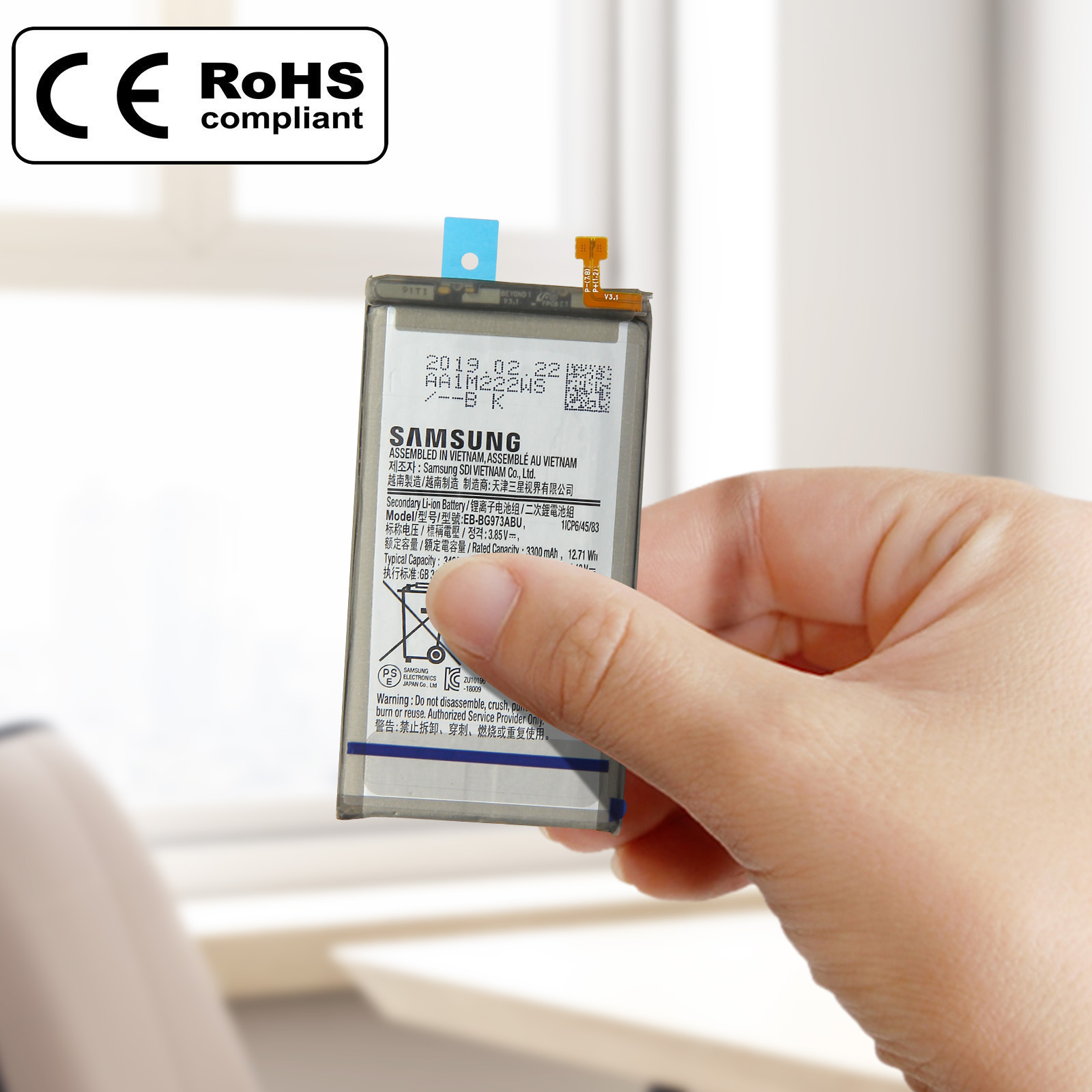 Eine Hand hält eine Telefonbatterie mit Etiketten und Text. Ein Aufkleber sagt RoHS-konform.