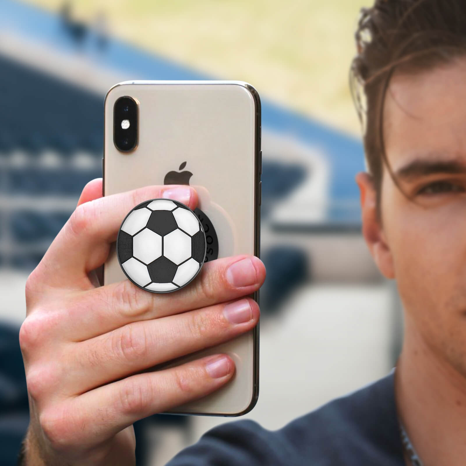 Eine Person, die ein Telefon mit einem Fußball-Popsocket hält.