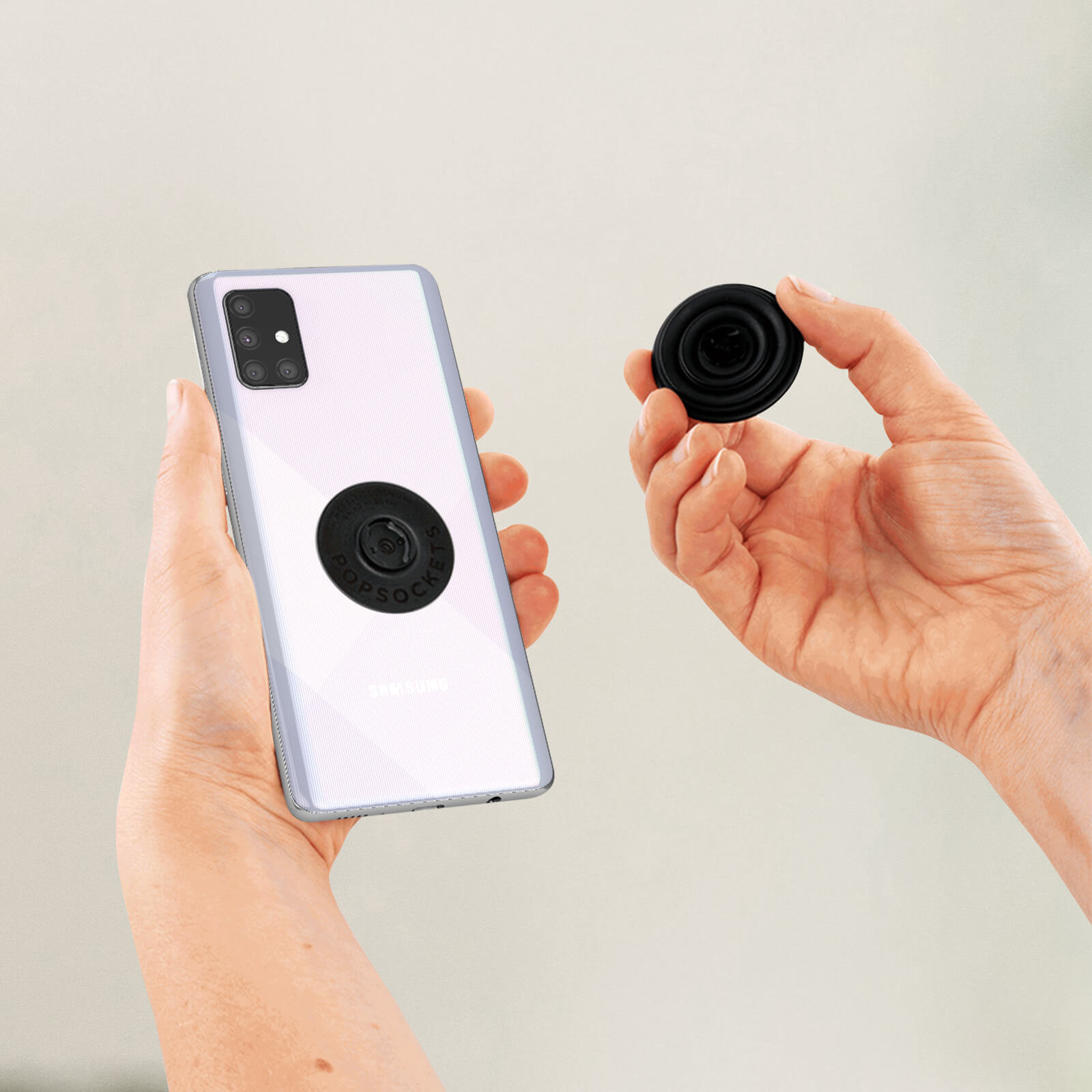 Hände halten ein Telefon mit einem schwarzen Pop-Socket und einem weiteren daneben. Das Telefon ist weiß.