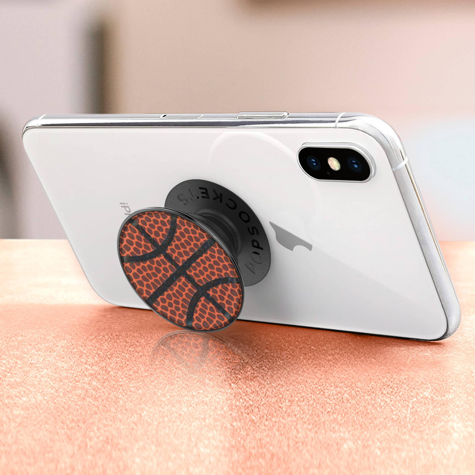 Ein weißes Telefon mit einem Basketball-Popsocket auf einer hellen Oberfläche.