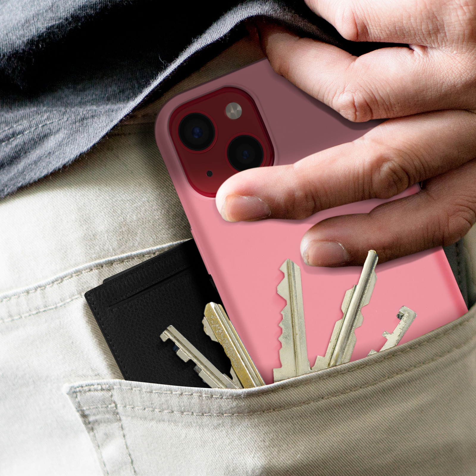 Main fouillant dans une poche avec clés et porte-cartes noir, téléphone avec coque rose à l'intérieur.