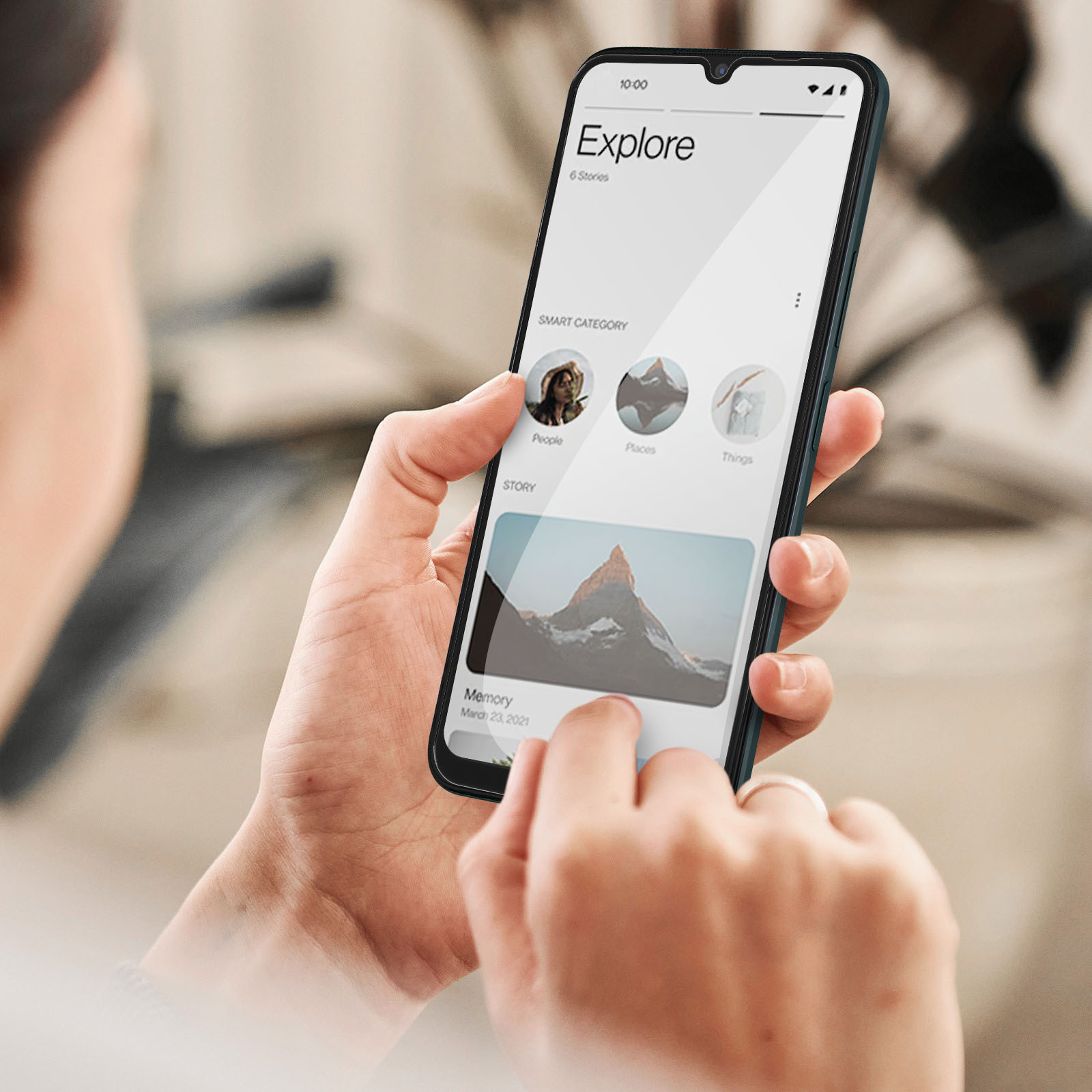 Personne tenant un téléphone. Le téléphone affiche l'application Explorer avec des catégories. Main au premier plan.