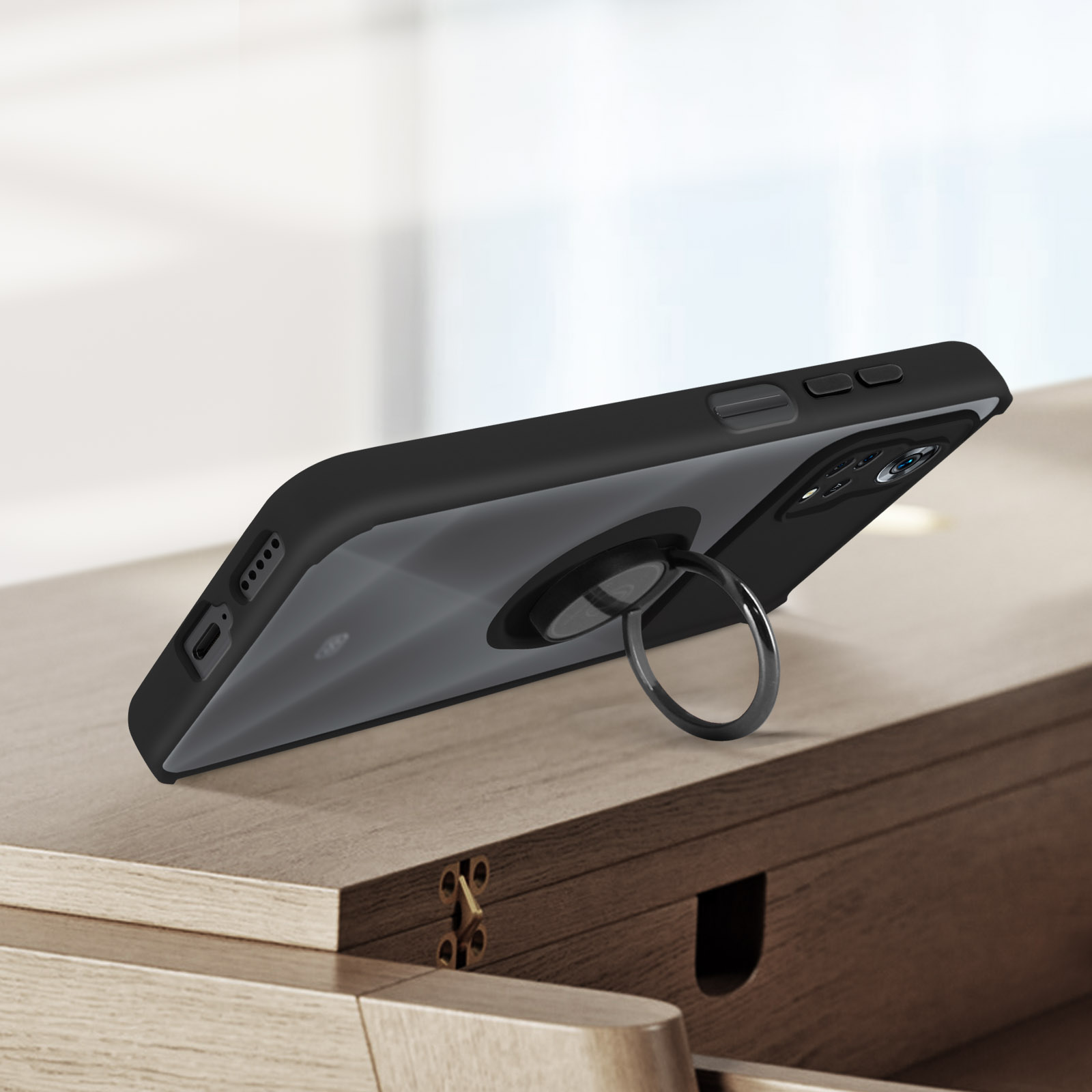 Coque de téléphone noire avec support d'anneau. La coque est sur une surface en bois.