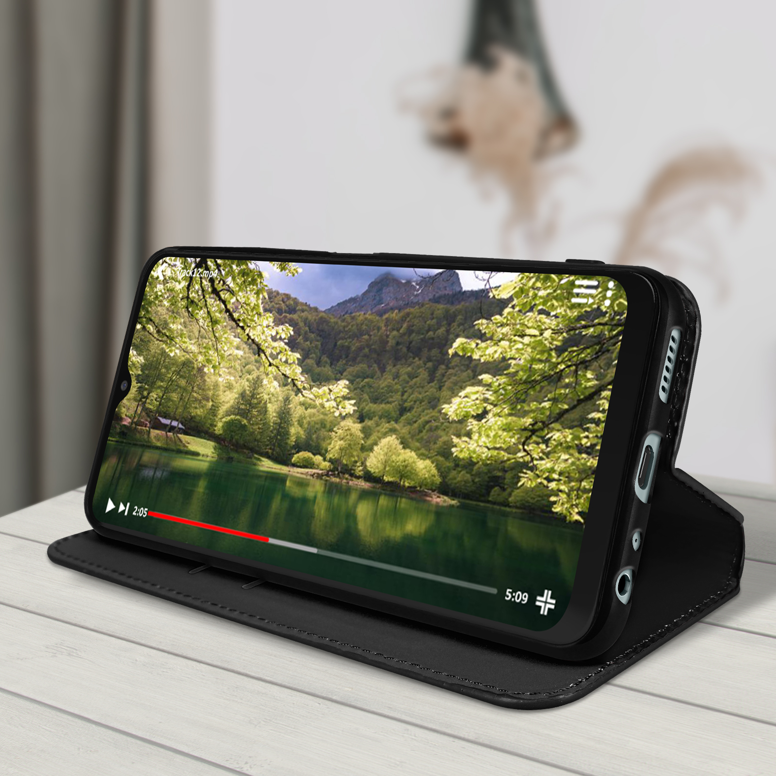 Telefono nero in custodia a libro nera, che mostra una scena del lago. La custodia è su un tavolo.