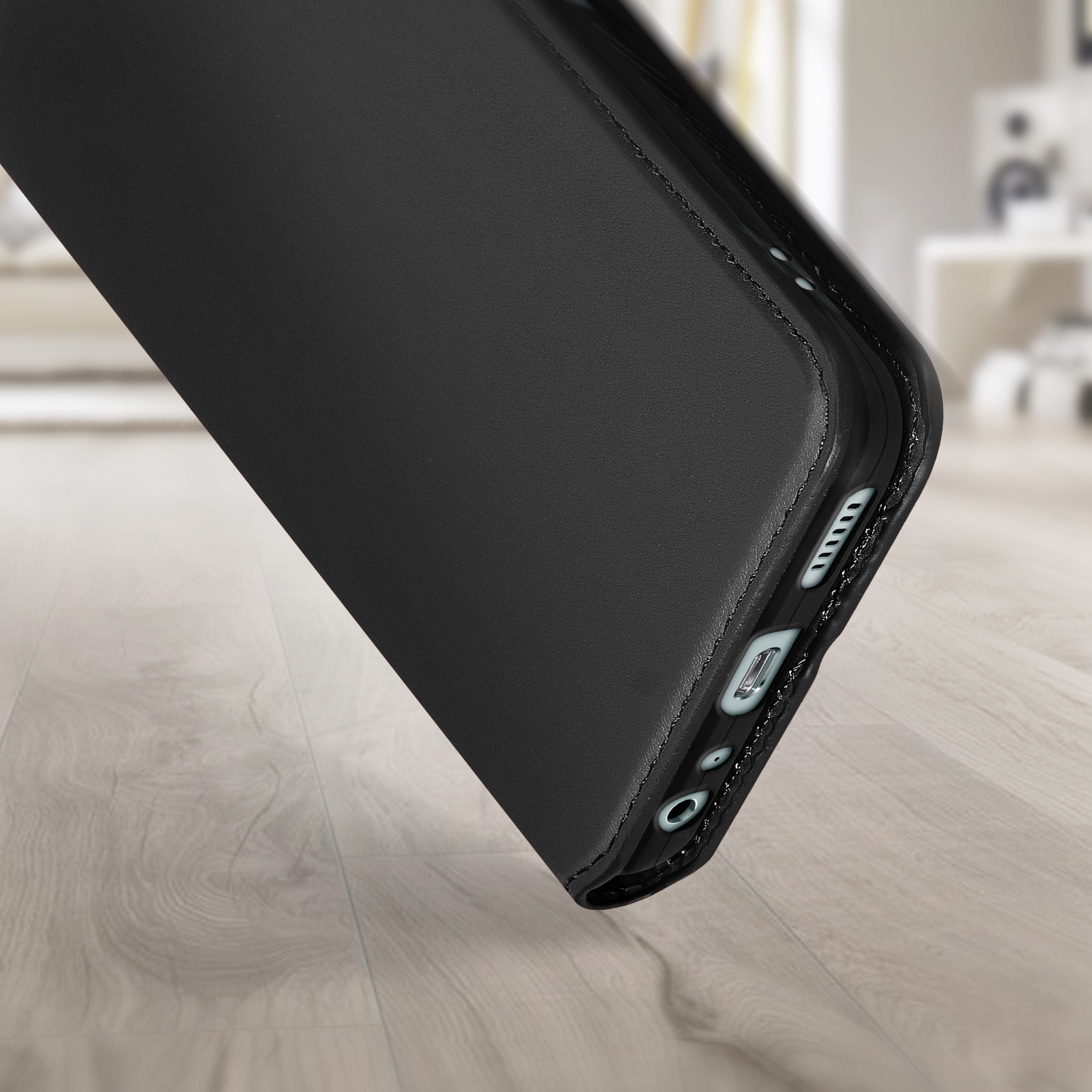 Custodia per telefono nera, che mostra le porte inferiori, su un pavimento in legno.