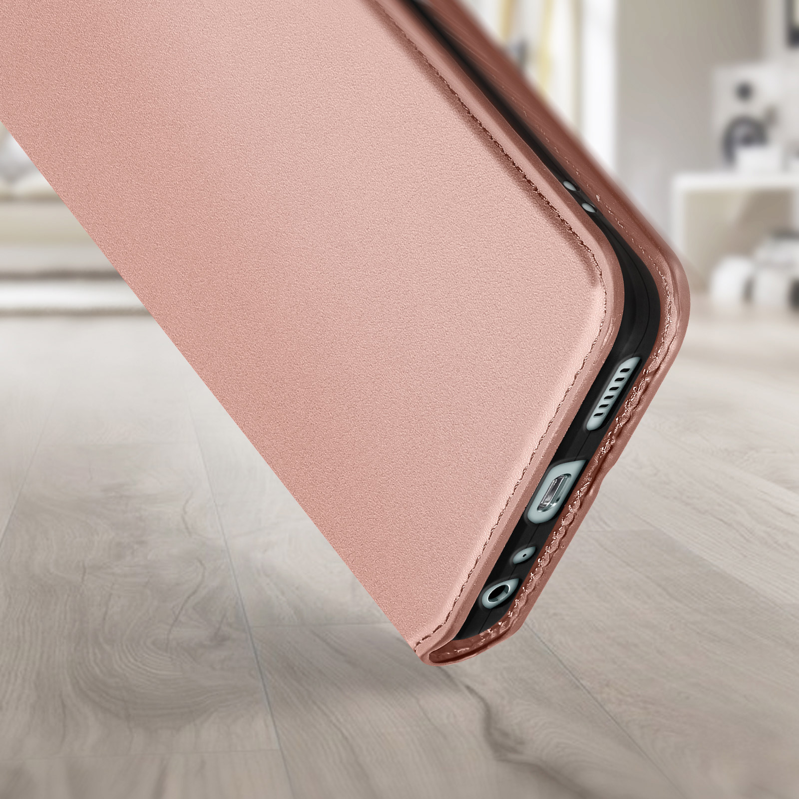 Custodia per telefono oro rosa con texture in pelle, angolata su superficie in legno.