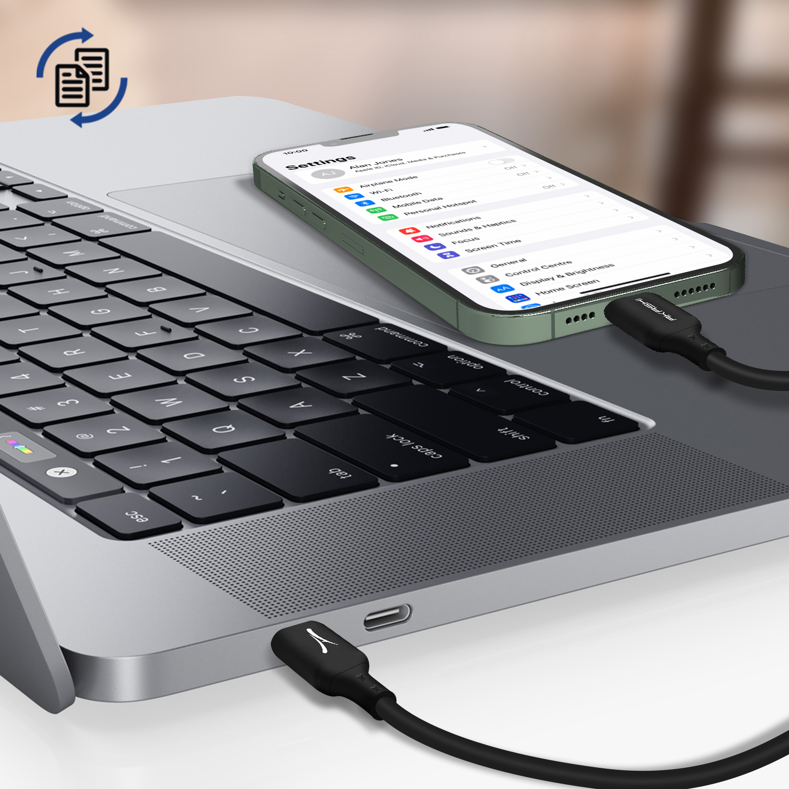 Un laptop con un telefono che mostra le impostazioni, collegato con un cavo nero. Il telefono è verde.
