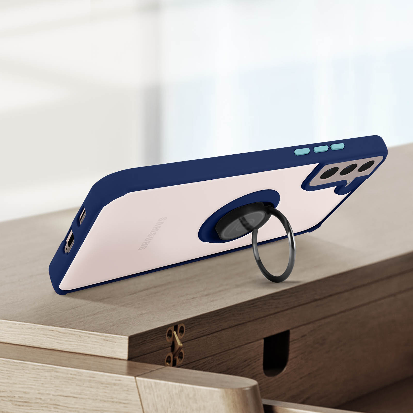 Coque de téléphone avec anneau de maintien sur une surface en bois. La coque a un cadre bleu et un dos blanc.
