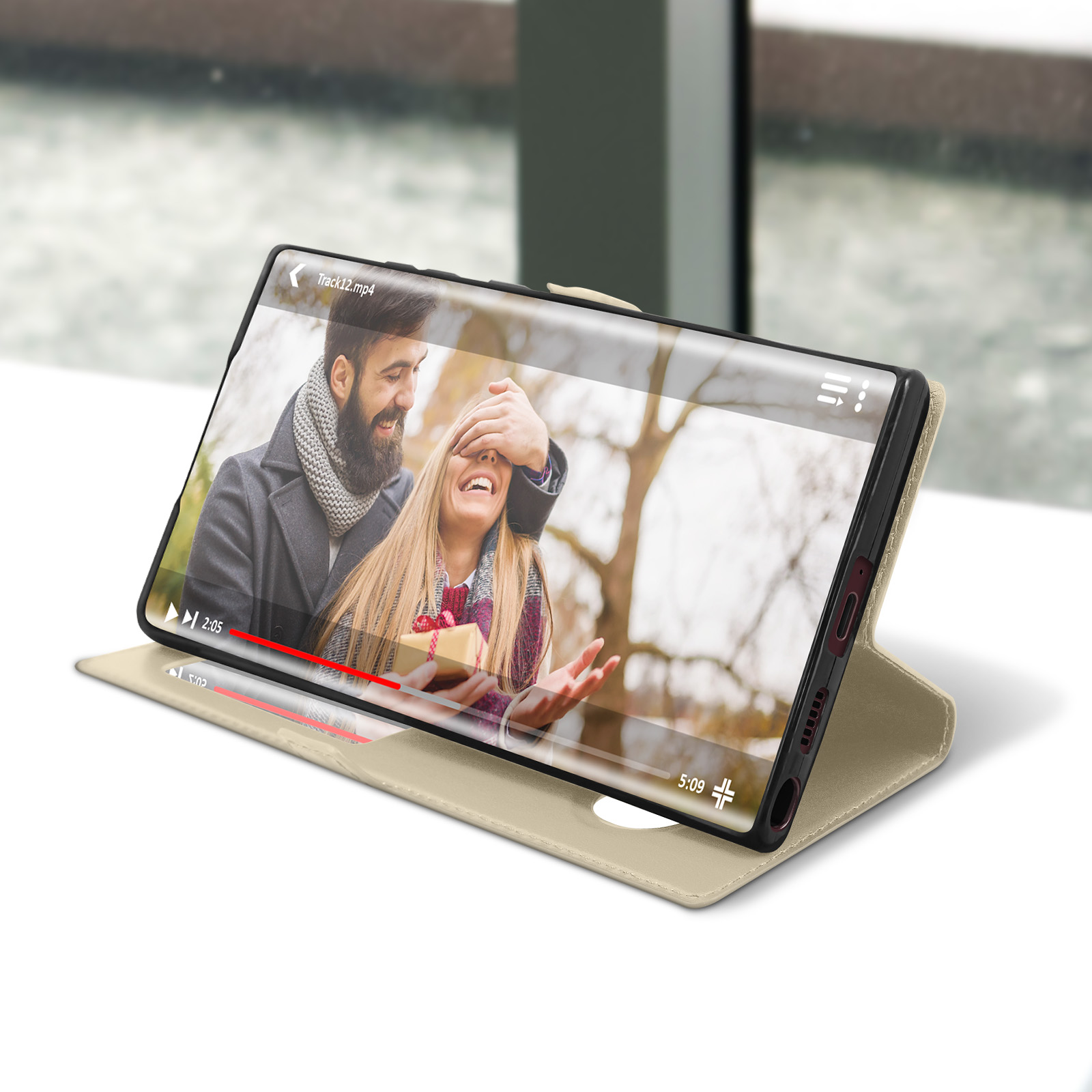 Téléphone dans un étui affichant une vidéo d'un couple. Le téléphone repose sur une surface, avec un fond enneigé.
