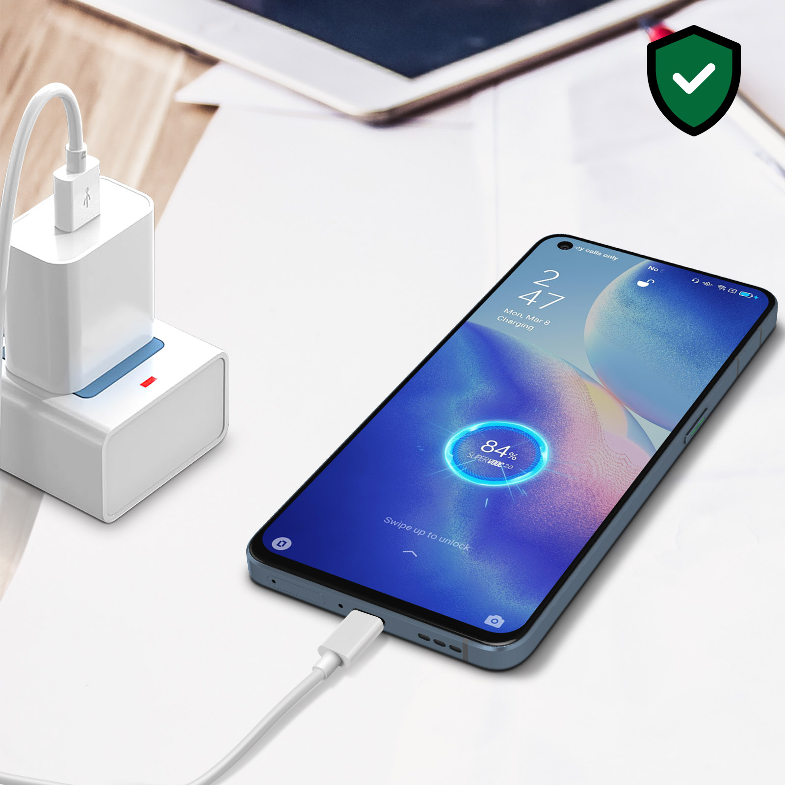 Teléfono cargando en un escritorio, con cargador, cable y un indicador de carga en la pantalla.