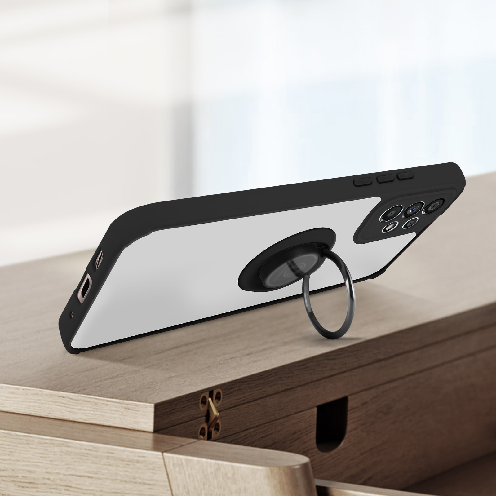 Un telefono con un supporto ad anello è su una superficie di legno. Il retro è bianco, i bordi sono neri.