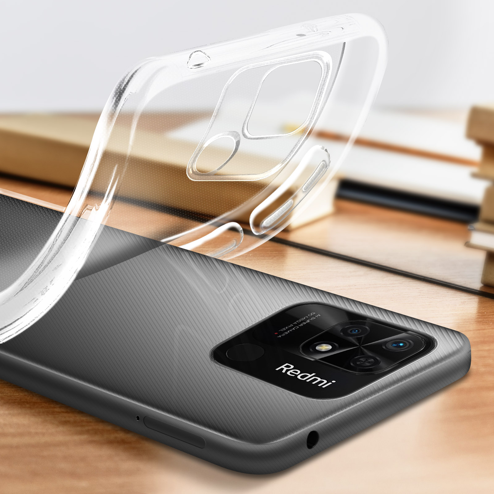 Funda transparente sobre un teléfono Redmi gris. Libro y superficie de madera al fondo.