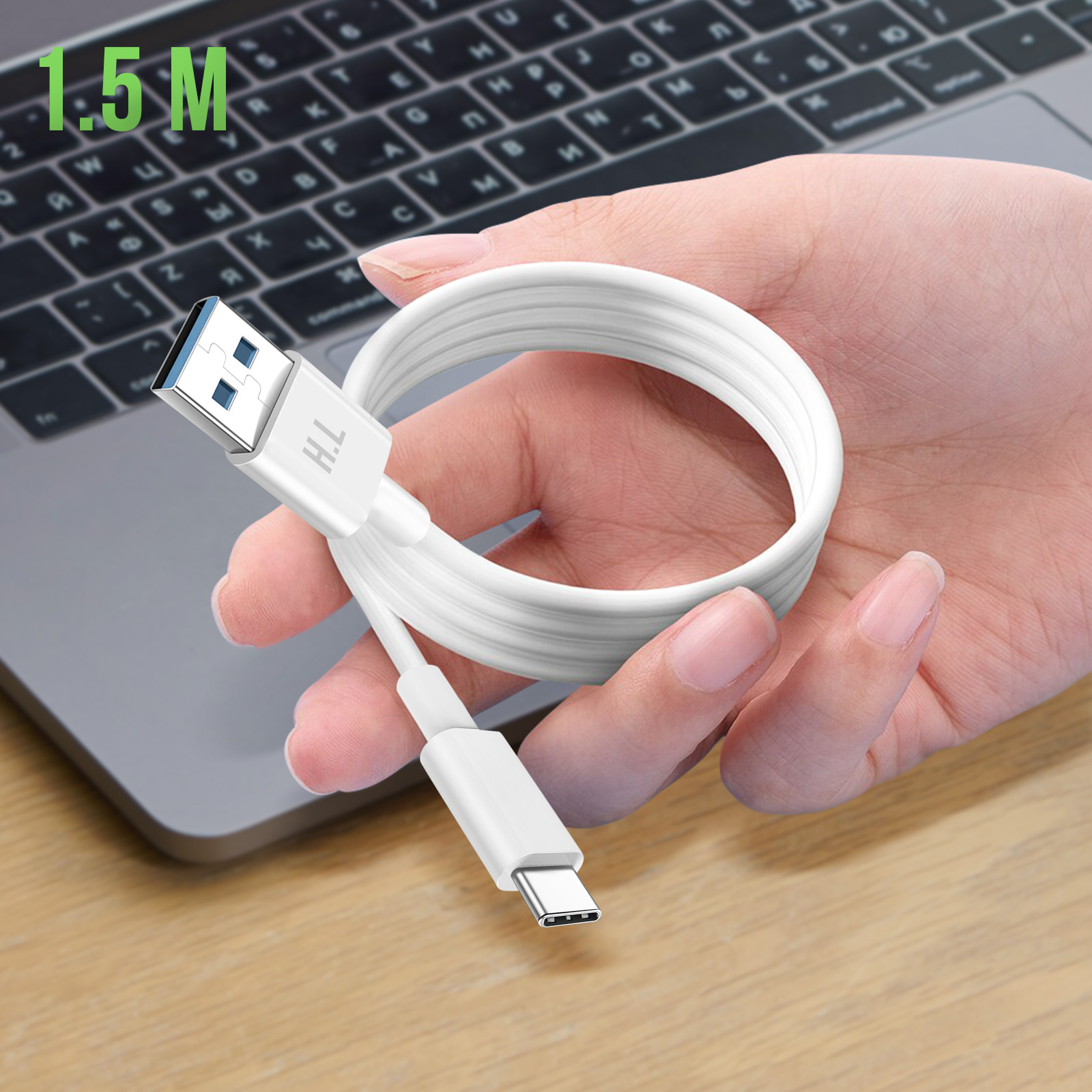 Un cavo da USB a USB-C bianco tenuto in mano, con un laptop sullo sfondo.