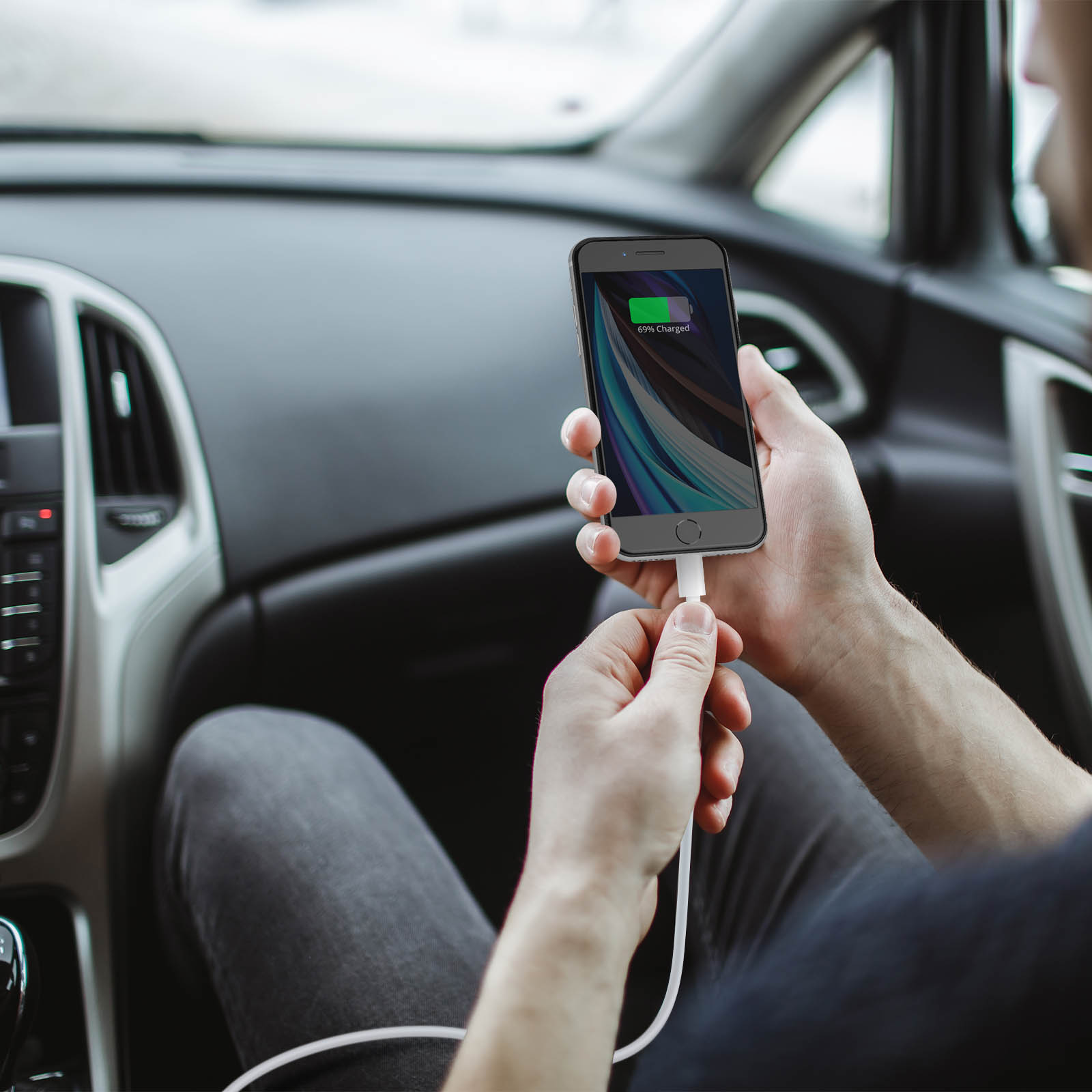 Person im Auto lädt Handy, Handy zeigt 69% geladen.