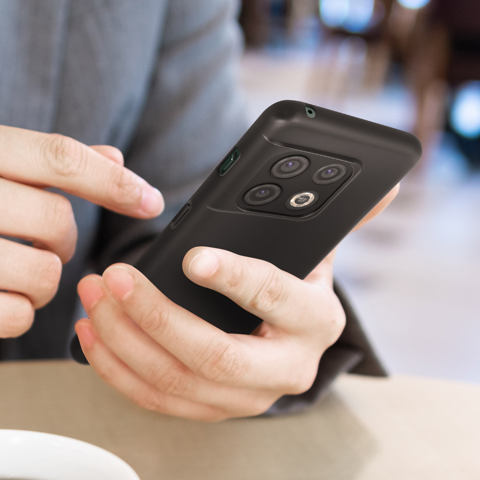 Handen die een zwarte telefoon in een hoesje vasthouden.