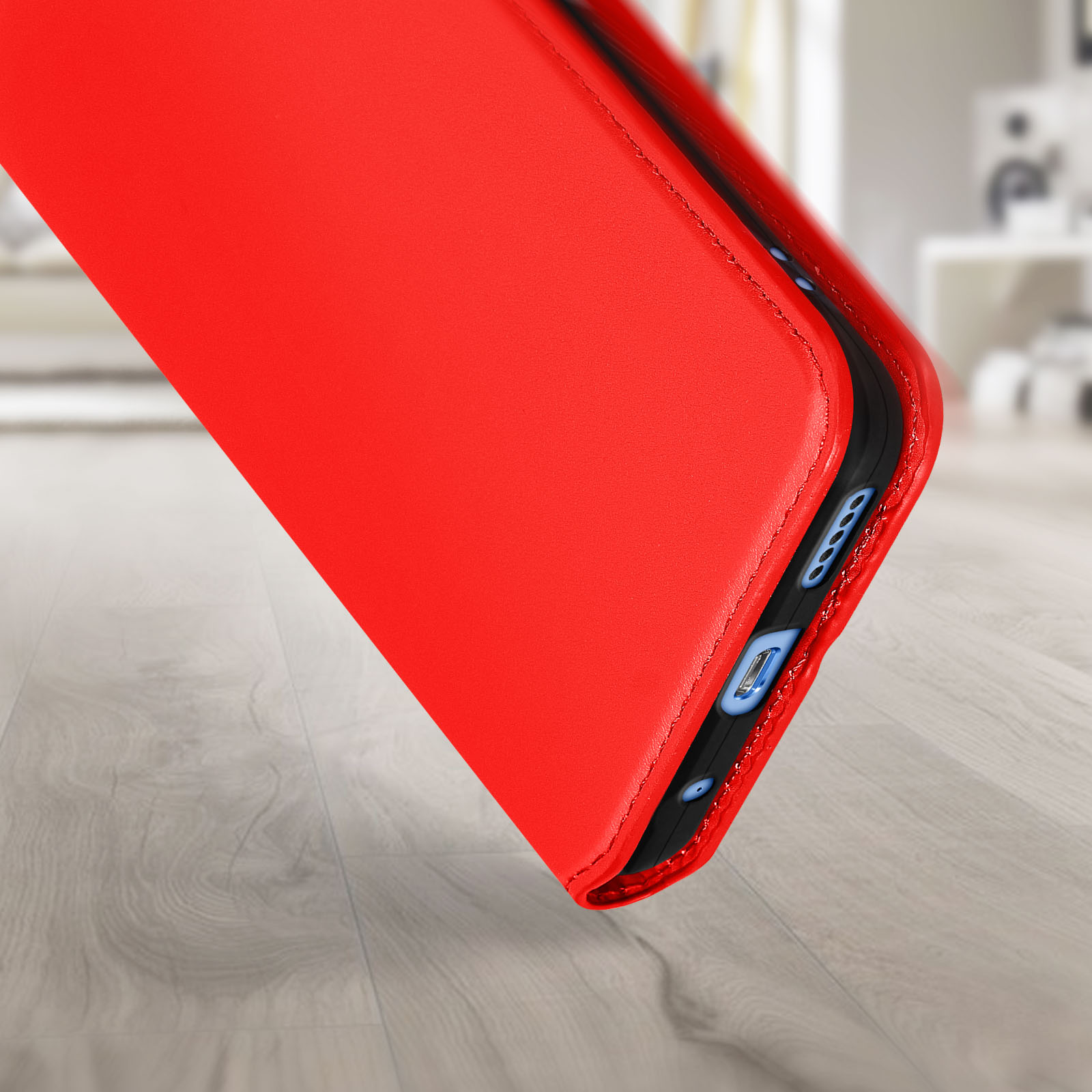 Coque de téléphone rouge, partiellement ouverte, montrant l'intérieur. Fond de sol en bois.
