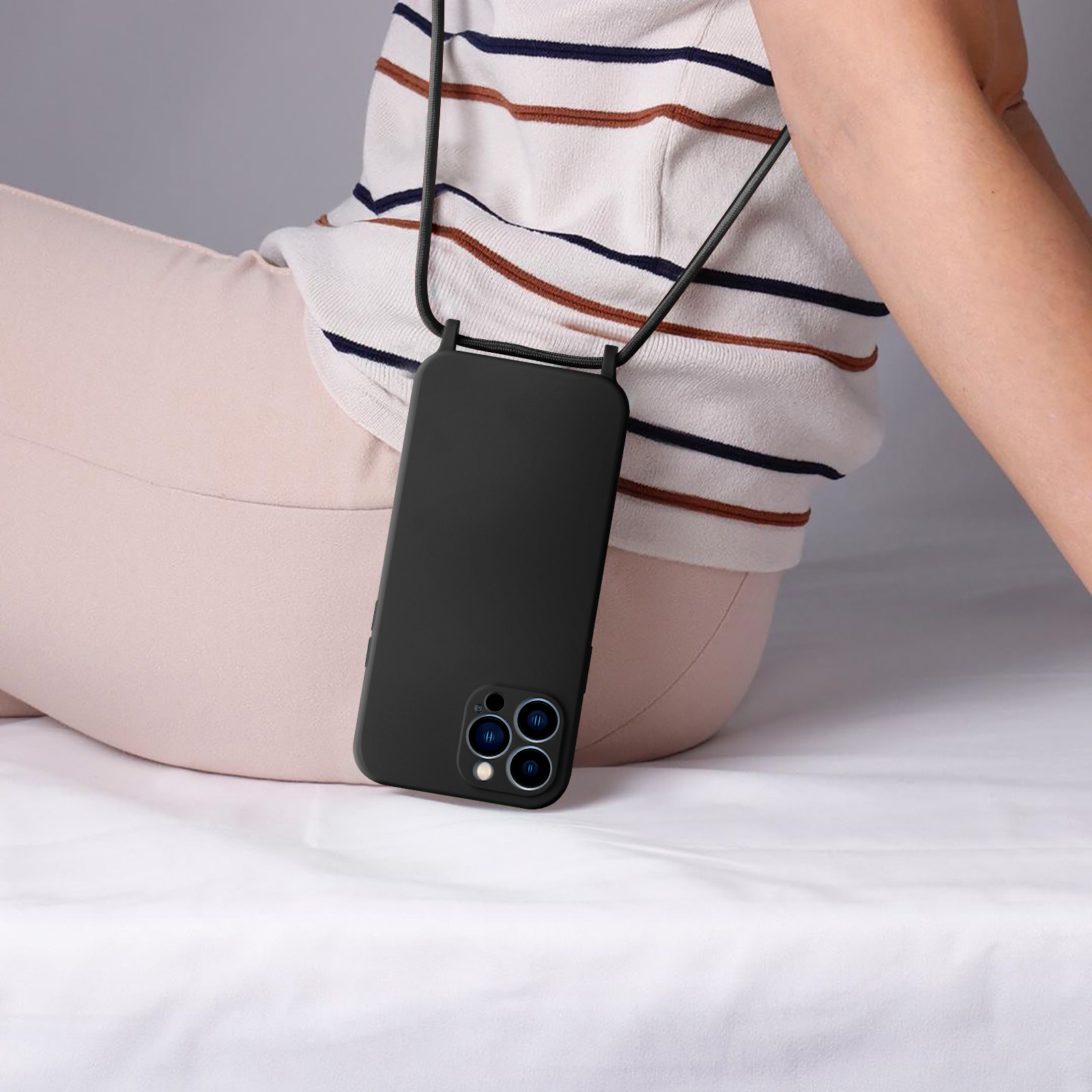 Persoon met een telefoonhoesje aan een lanyard. De telefoon is zwart en het hoesje is transparant.