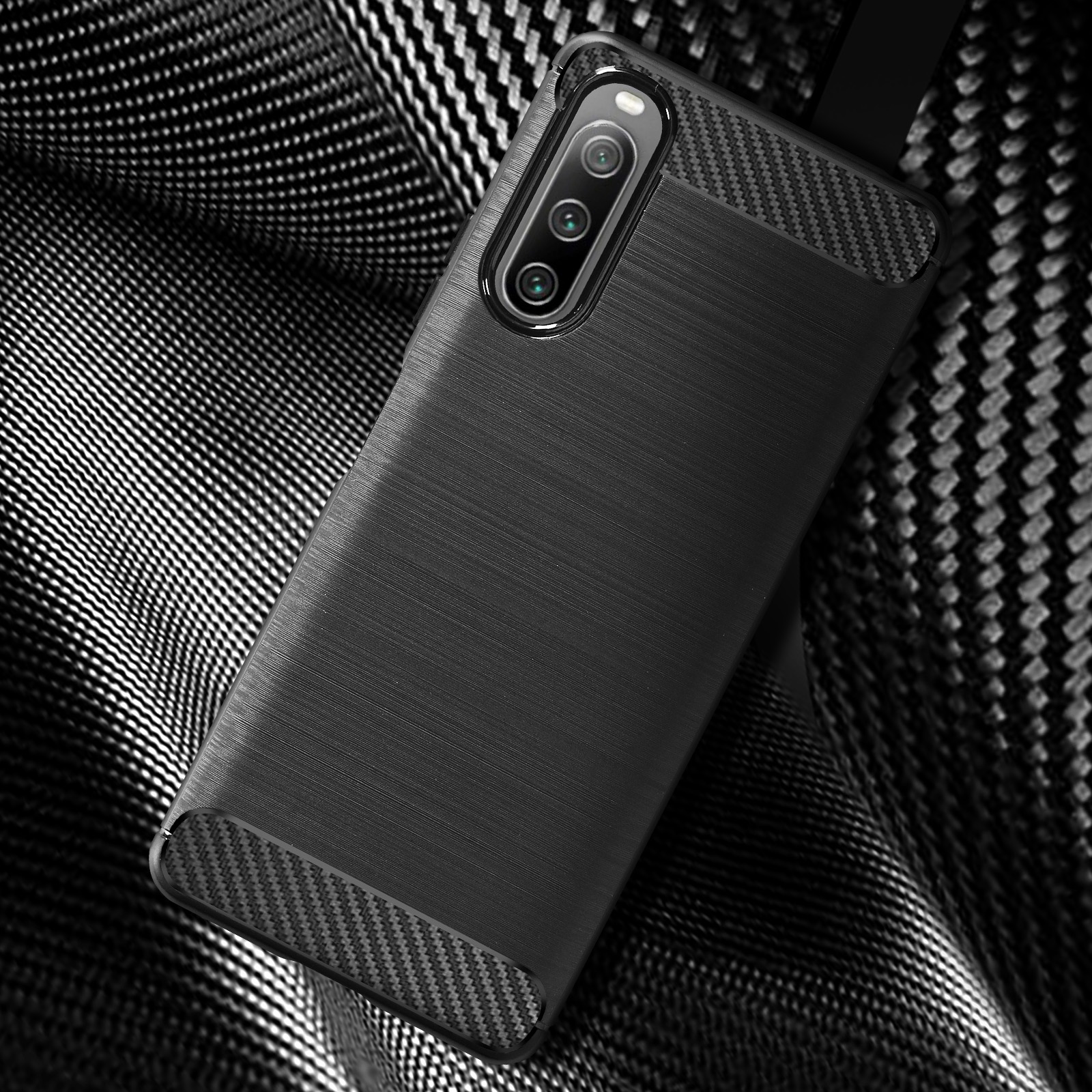 Custodia nera con texture in fibra di carbonio. Posizionata su una superficie a motivi.