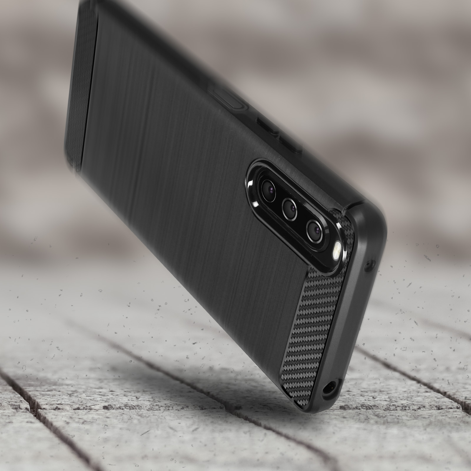 Custodia per telefono nera con una texture in metallo spazzolato su una superficie in legno. Sfondo sfocato.
