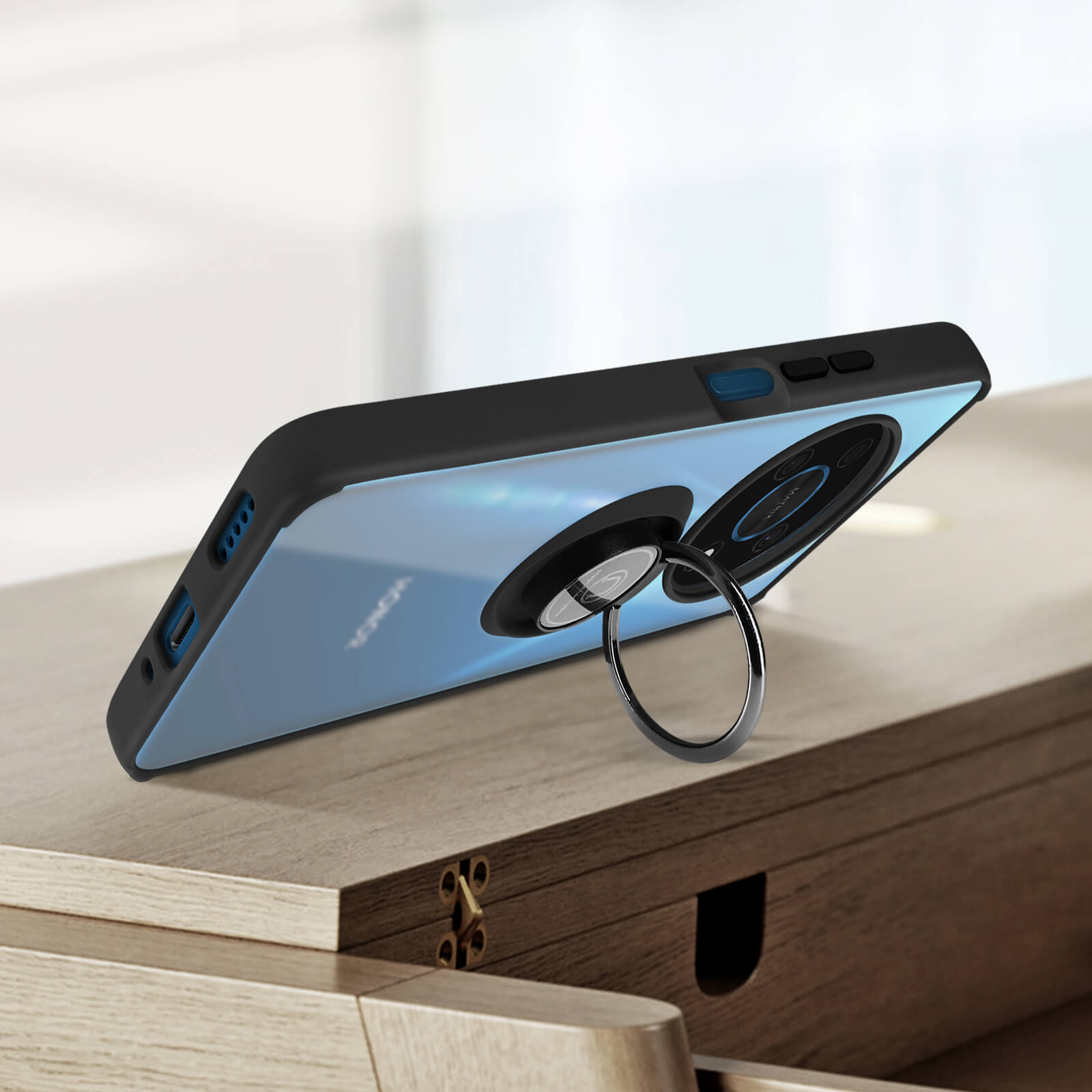 Telefono nero con supporto ad anello. Il telefono è su un tavolo di legno. Lo sfondo è sfocato.